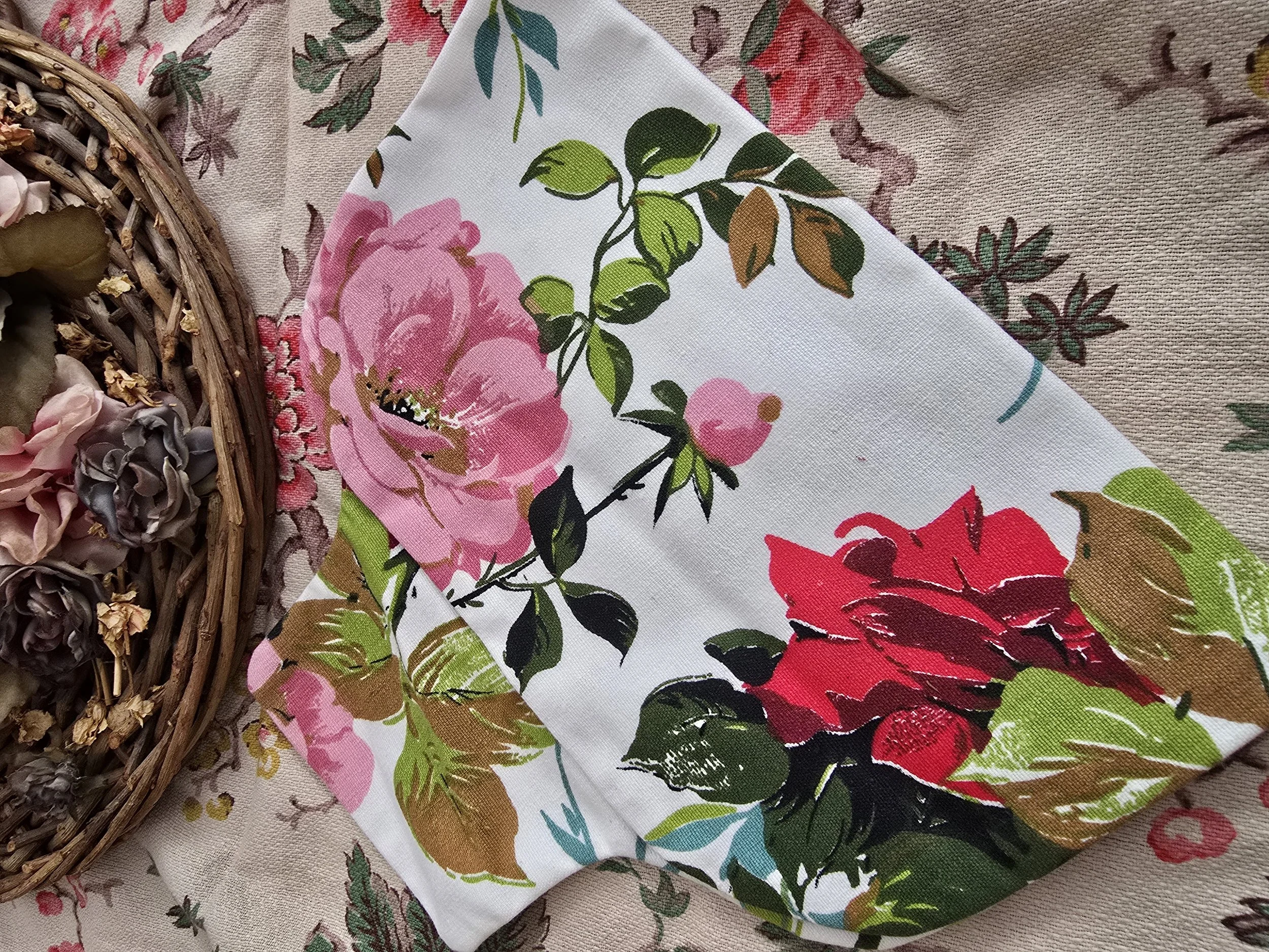 Close-up of vintage hot water bottle cover with pink and red roses on white cotton fabric.