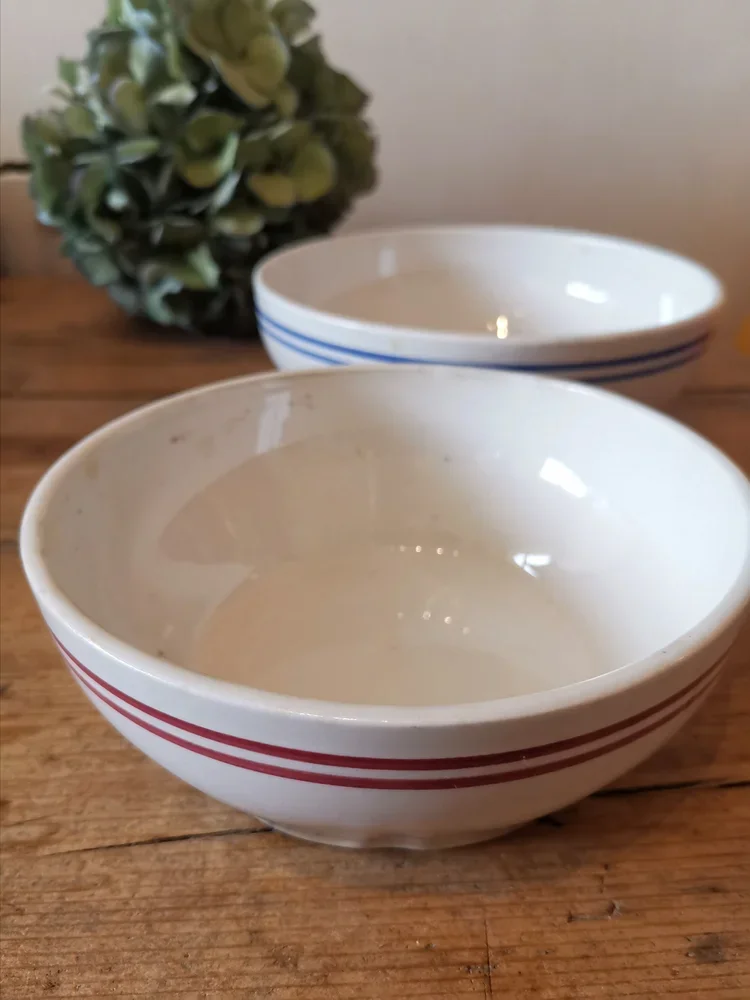 Stacked Moulin de Loups French bowls showing red and blue striped rims, rustic faience pottery.