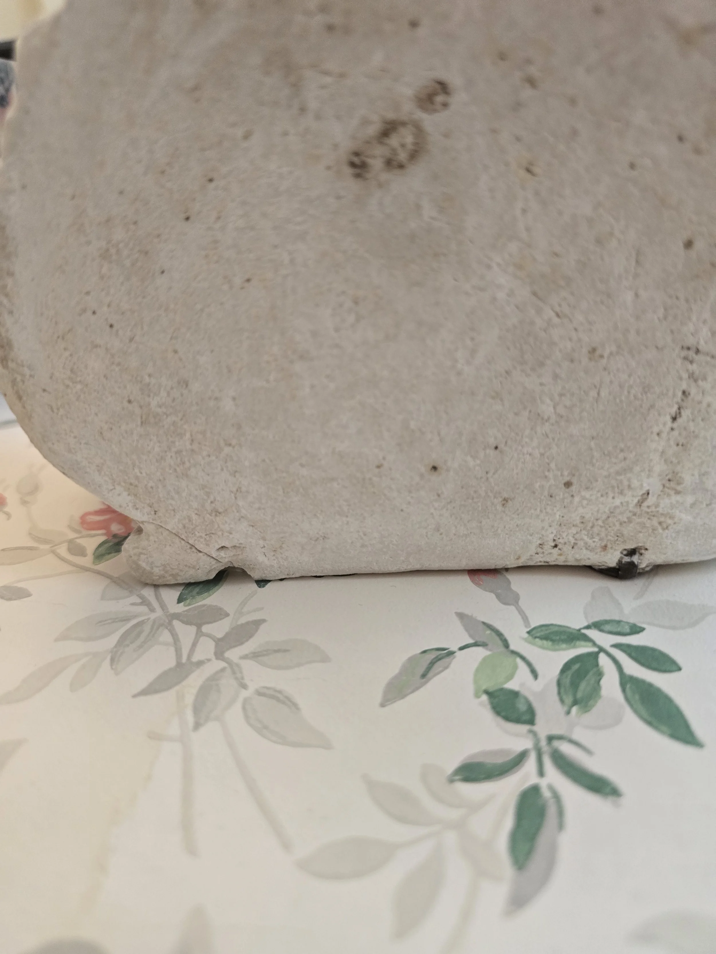 Weathered wall-mounted ornament with winged cherubs.