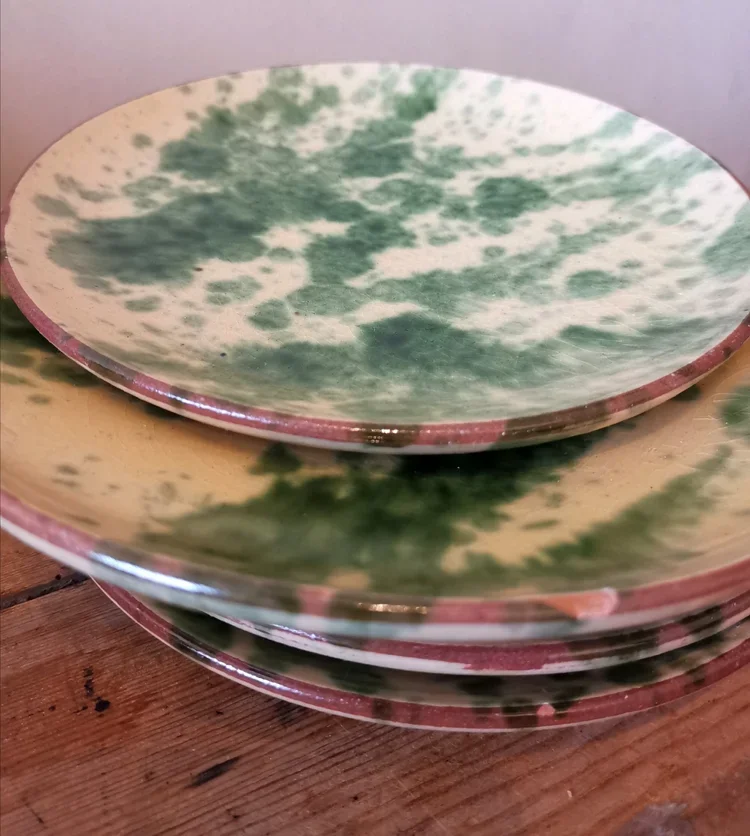 Close-up of stacked French terracotta side plates with olive green jaspé glaze