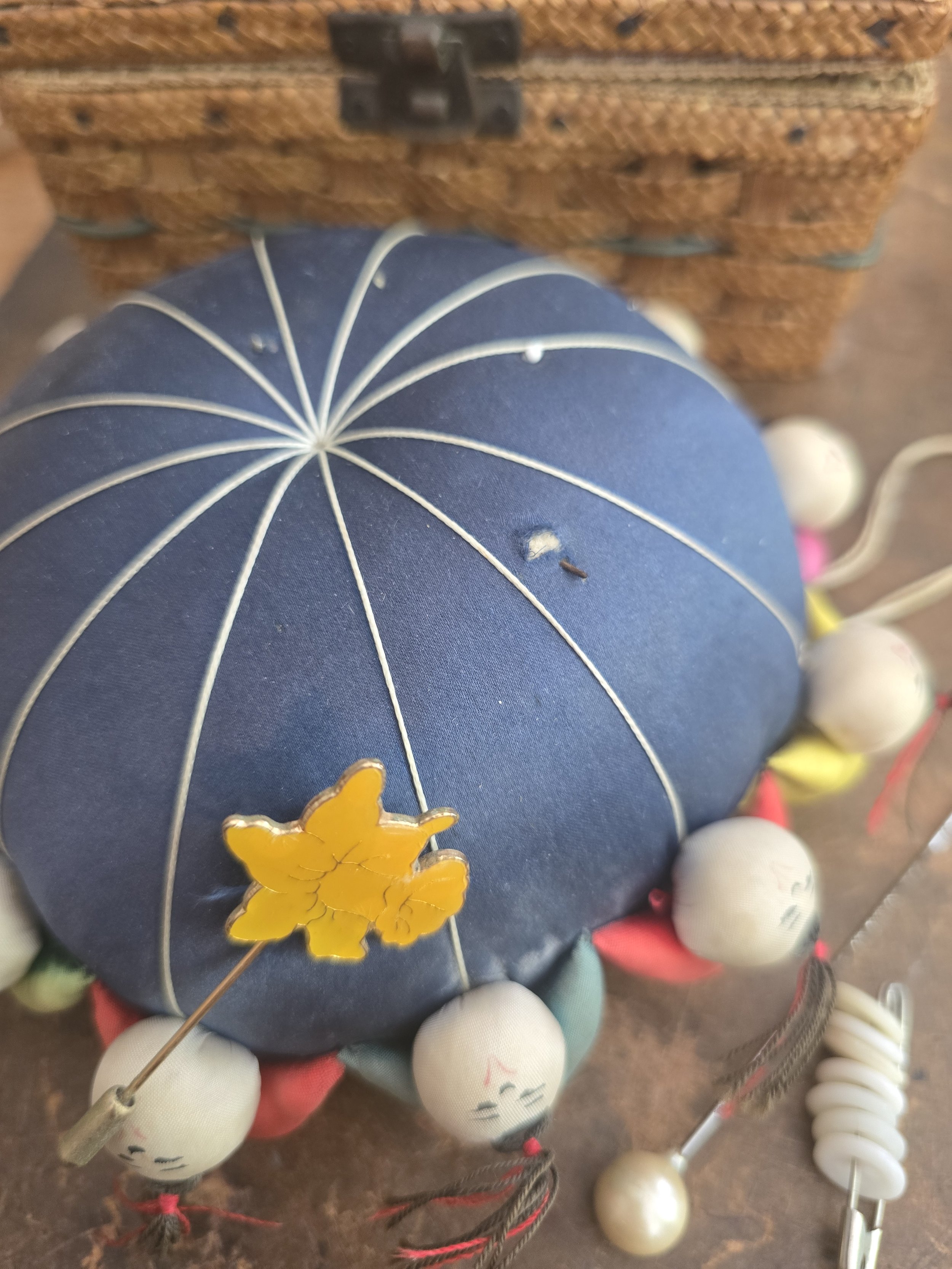 Vintage Asian pin cushion covered in navy fabric with radiating stitched design.