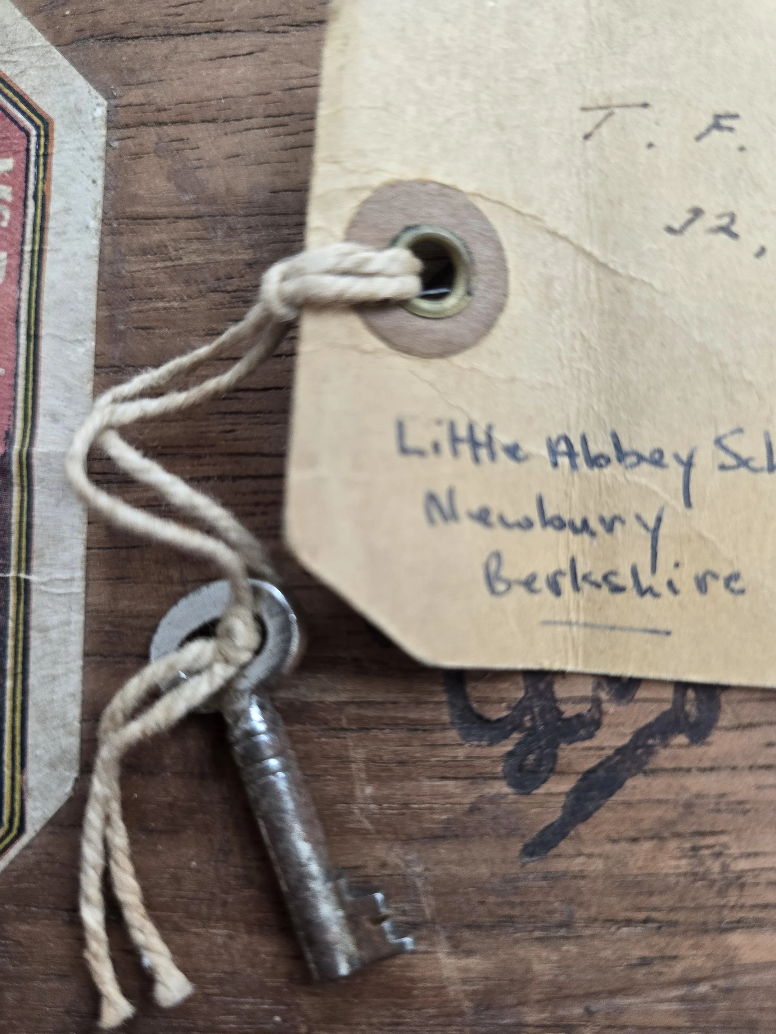 Old metal school trunk key tied with cotton cord to vintage manila luggage tag