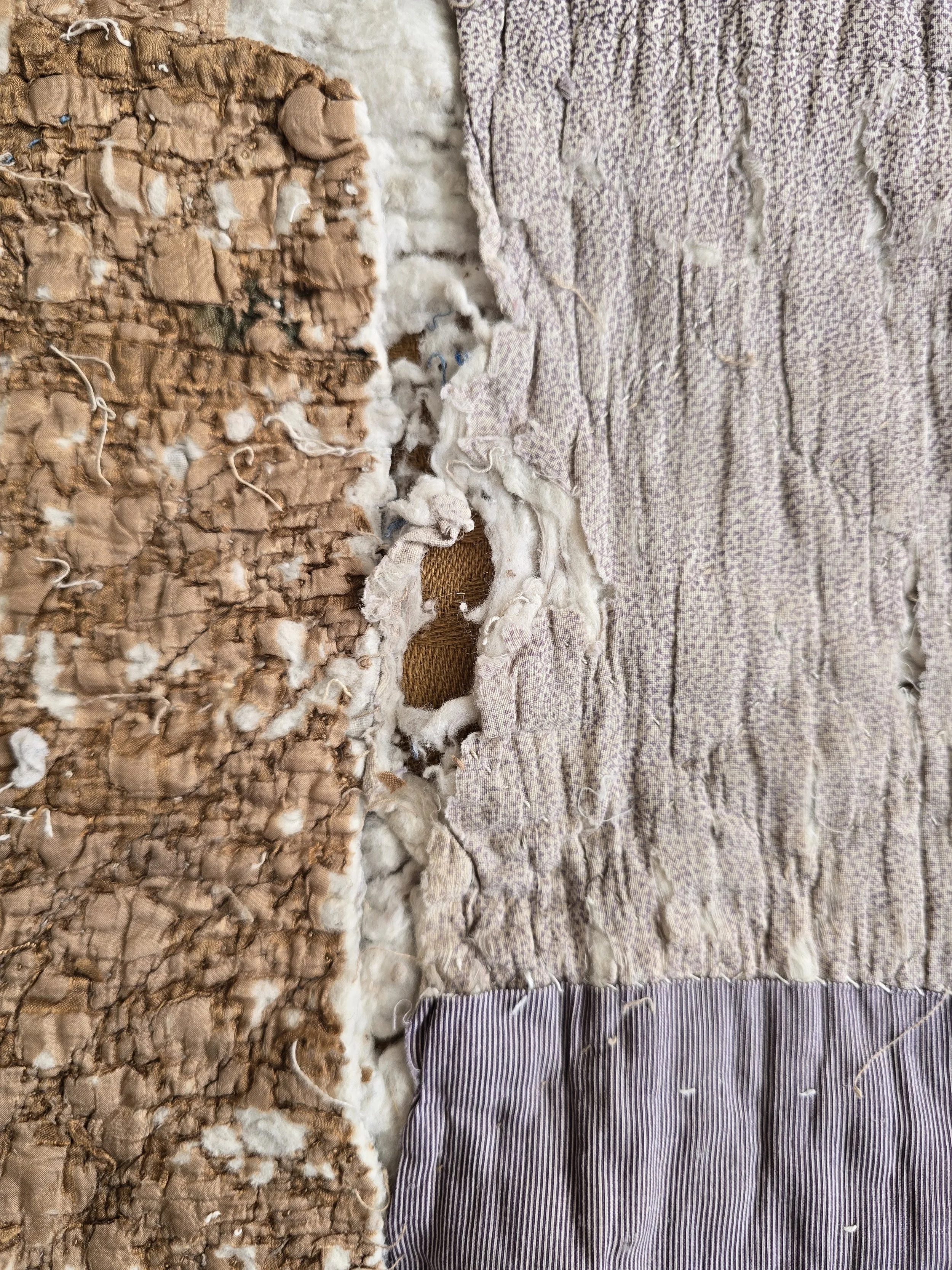 Antique French quilt fragment with faded purple printed cotton and exposed layers.