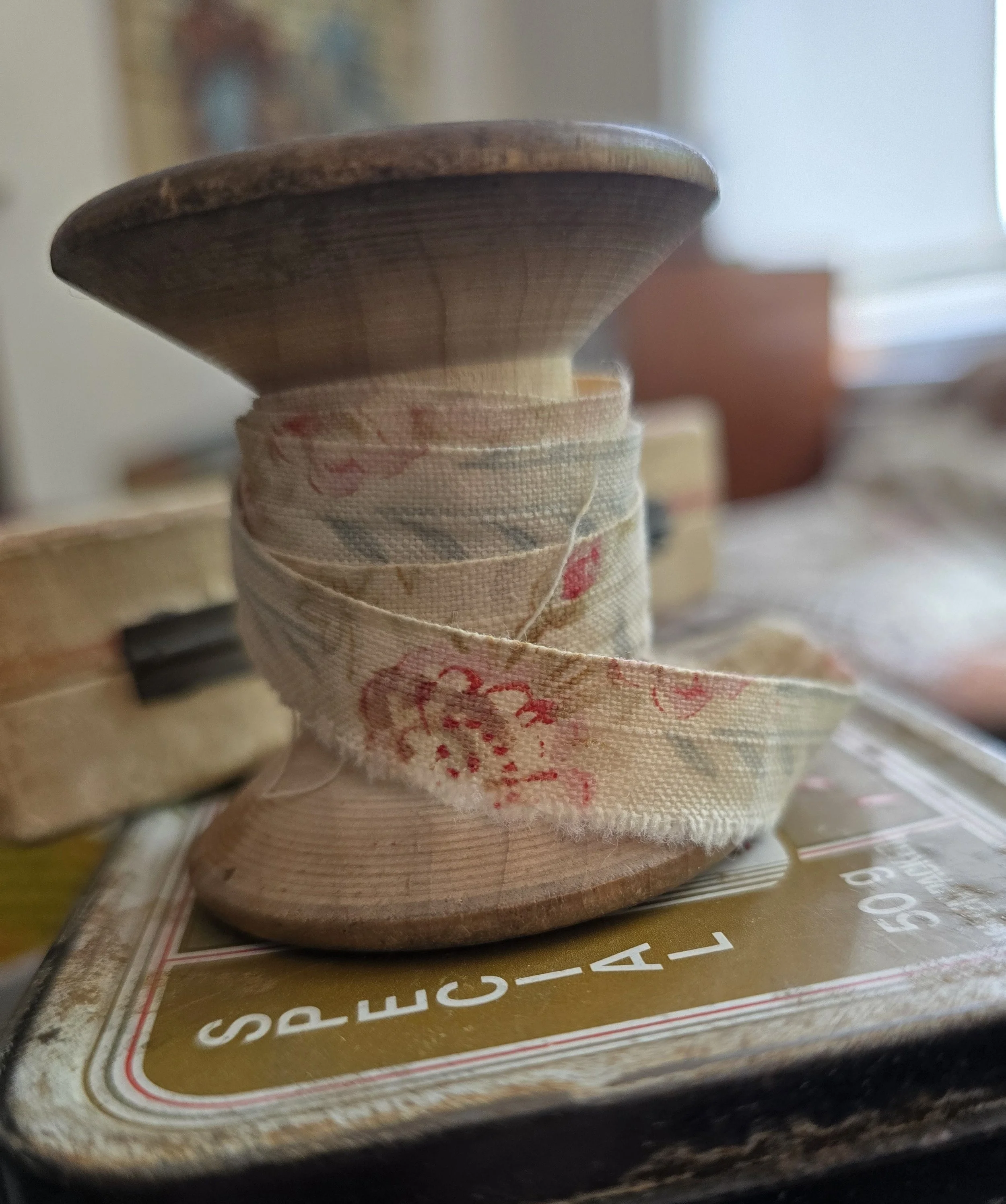 vintage wooden thread spool wrapped with faded antique fabric