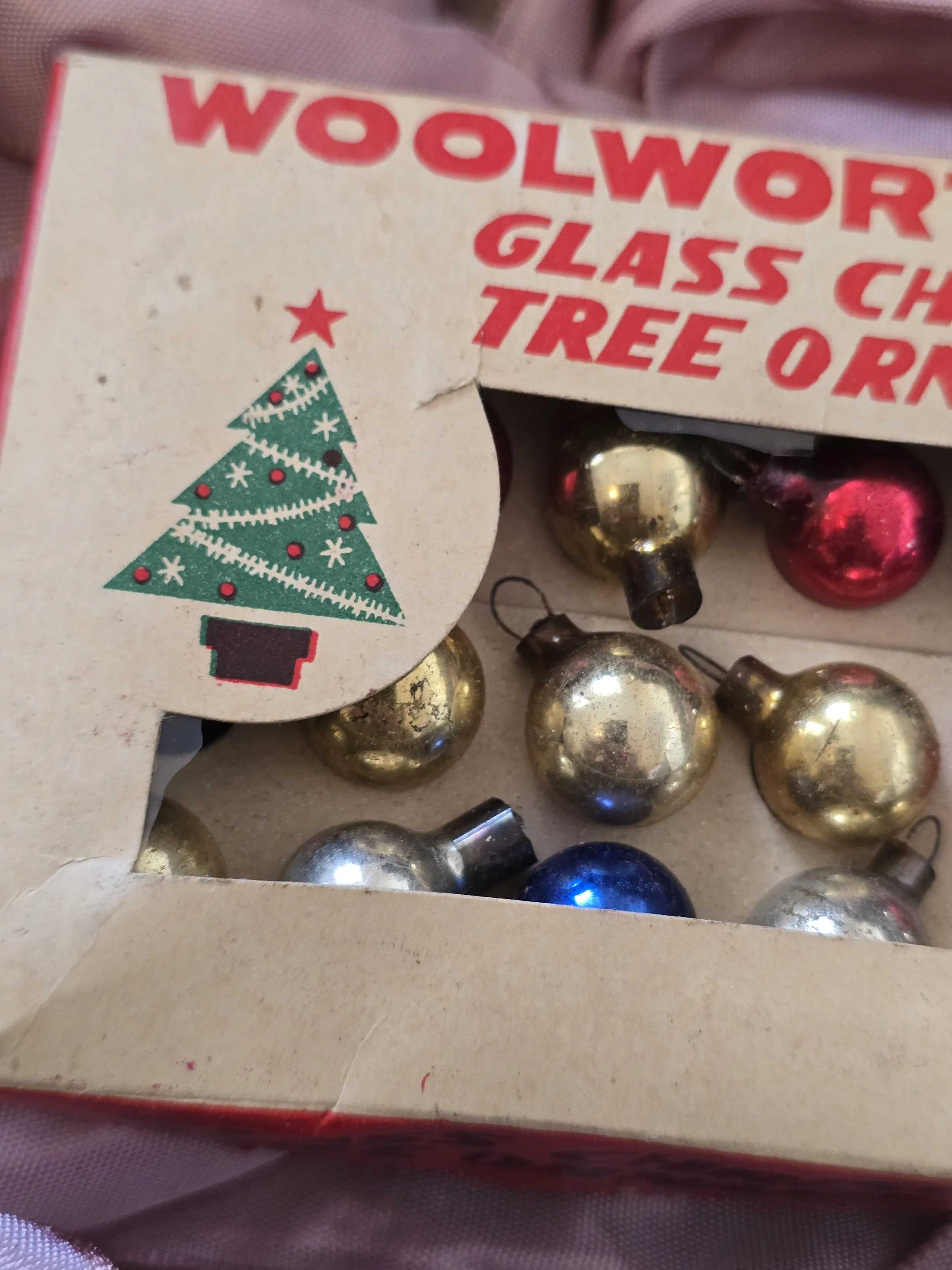 Close-up of vintage Woolworth Christmas ornament box with red lettering and illustrated green Christmas tree.