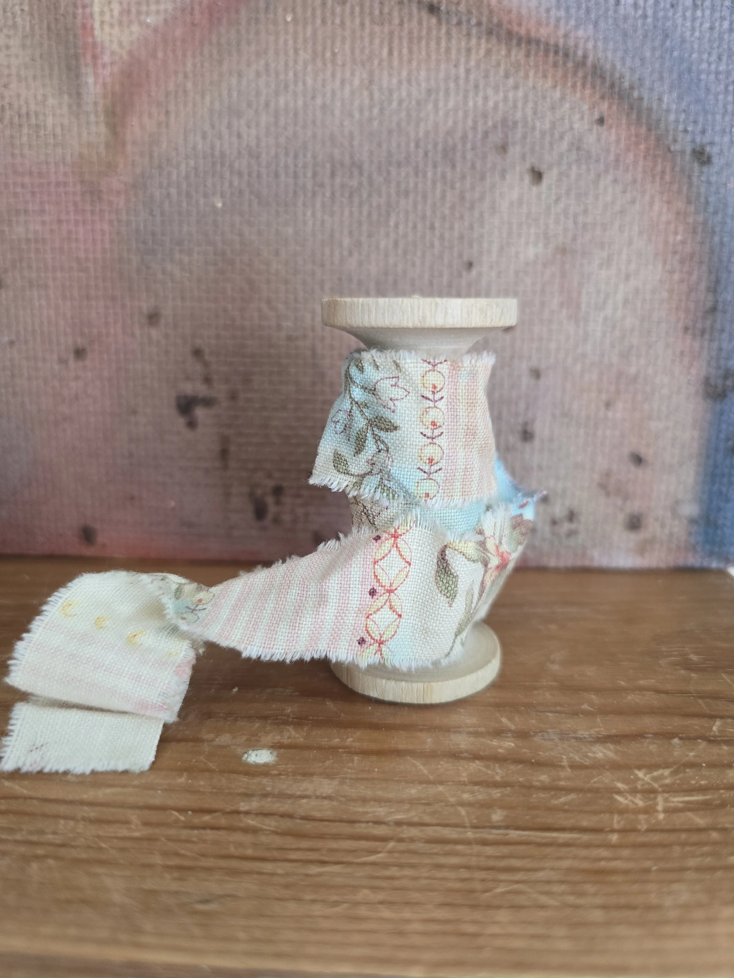 Vintage floral ribbon wound around a small wooden spool.
