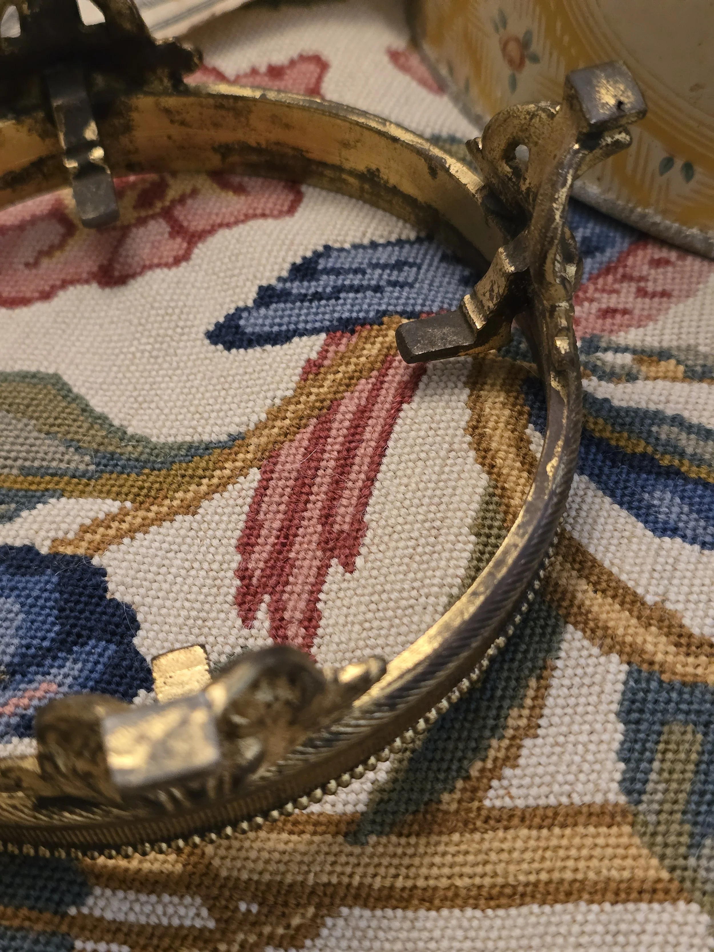 Detail of the aged gilded finish and metal supports on a small vintage decorative stand.