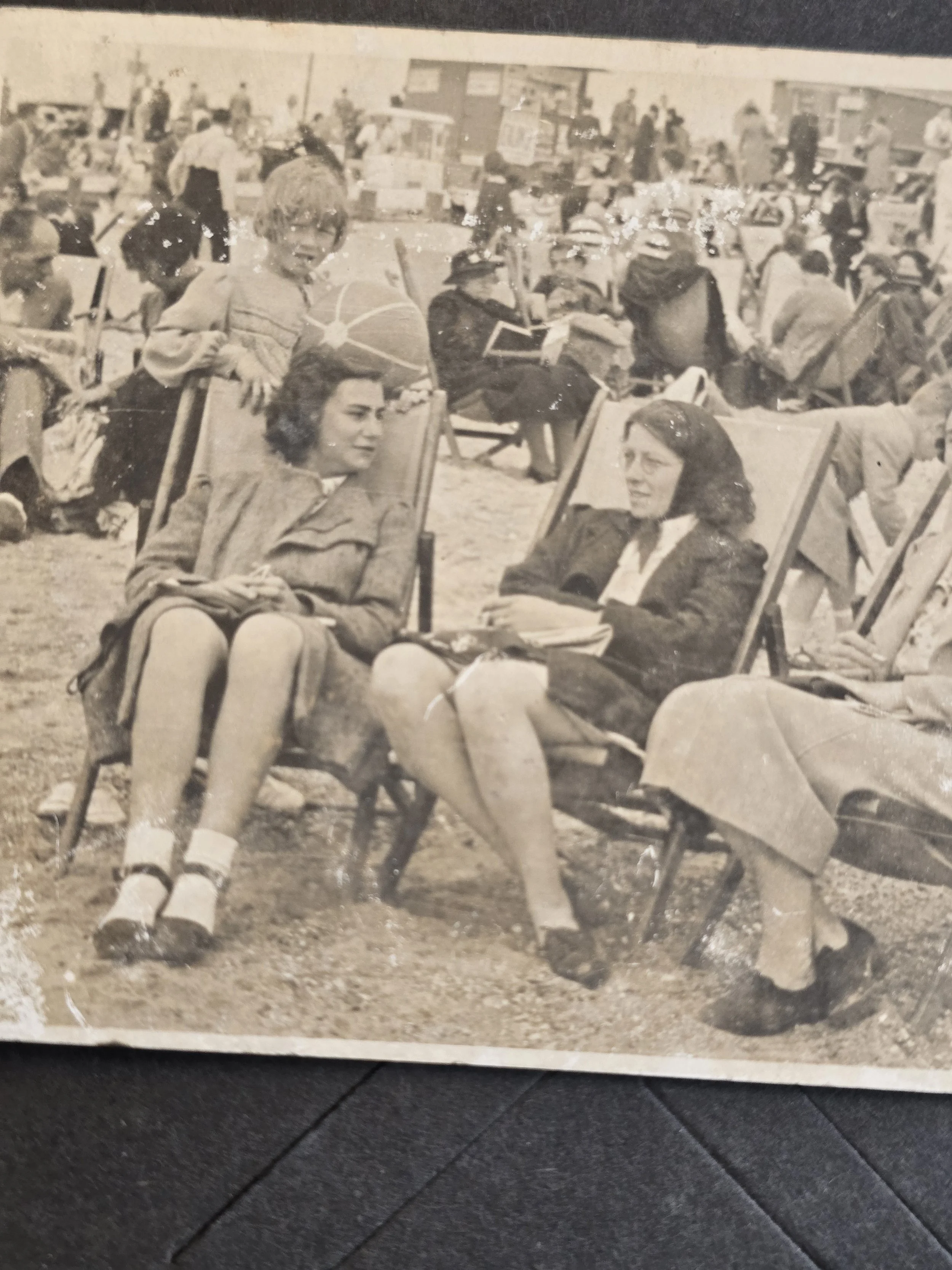 Vintage black and white photograph of a crowded British seaside resort with holidaymakers and deckchairs.