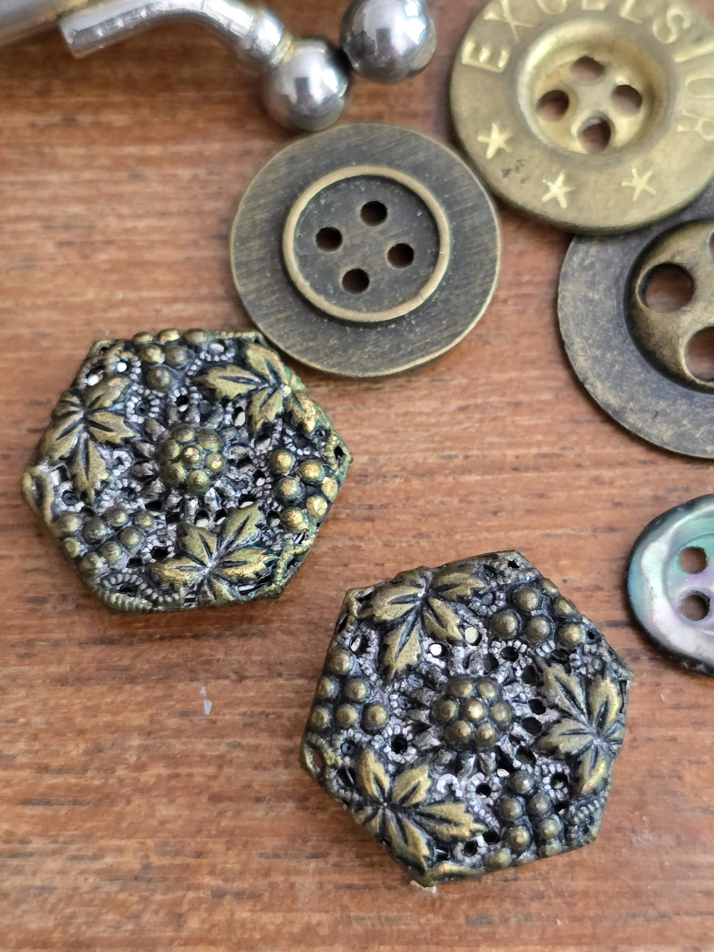 Decorative pair of antique floral metal buttons with aged brass patina.