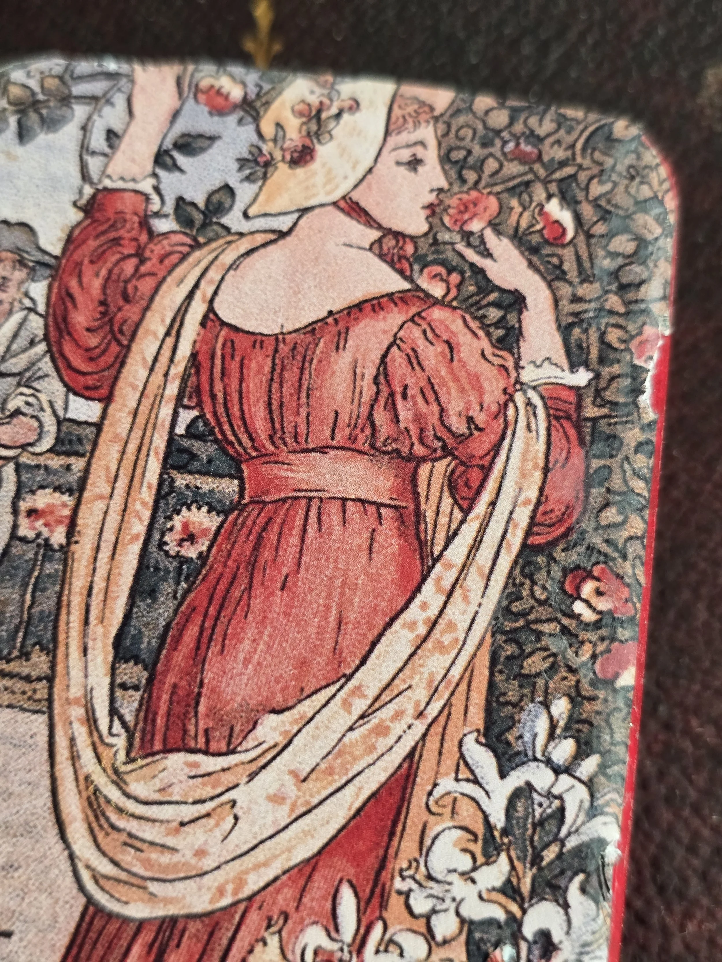Decorative vintage metal tin featuring a woman in a red dress surrounded by flowers, illustrated by Walter Crane.