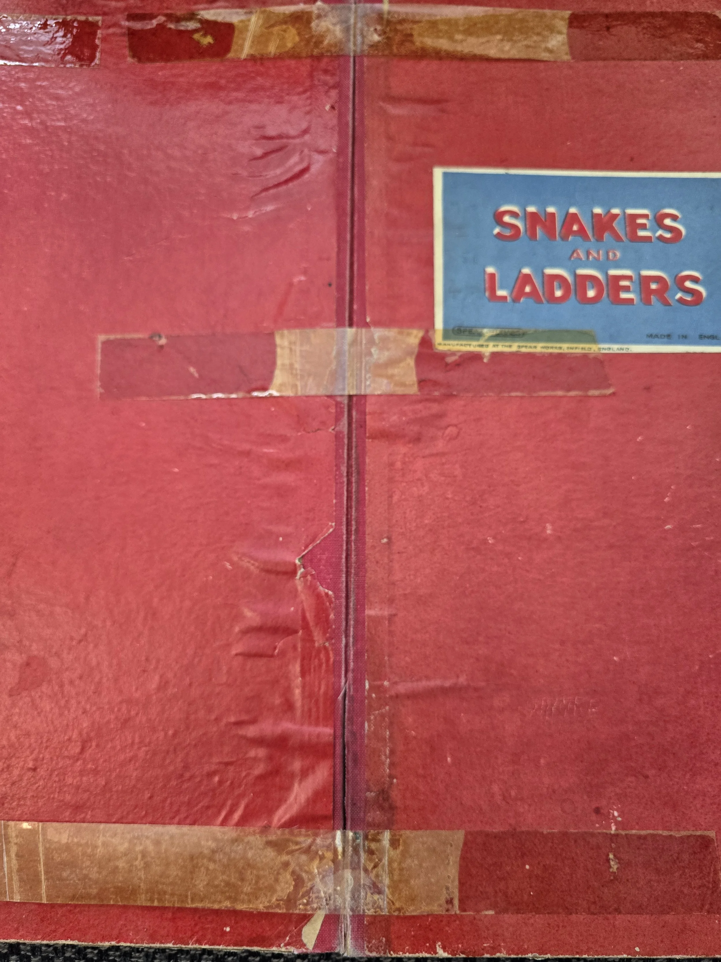 Reverse of vintage folding game board showing old tape repairs and wear