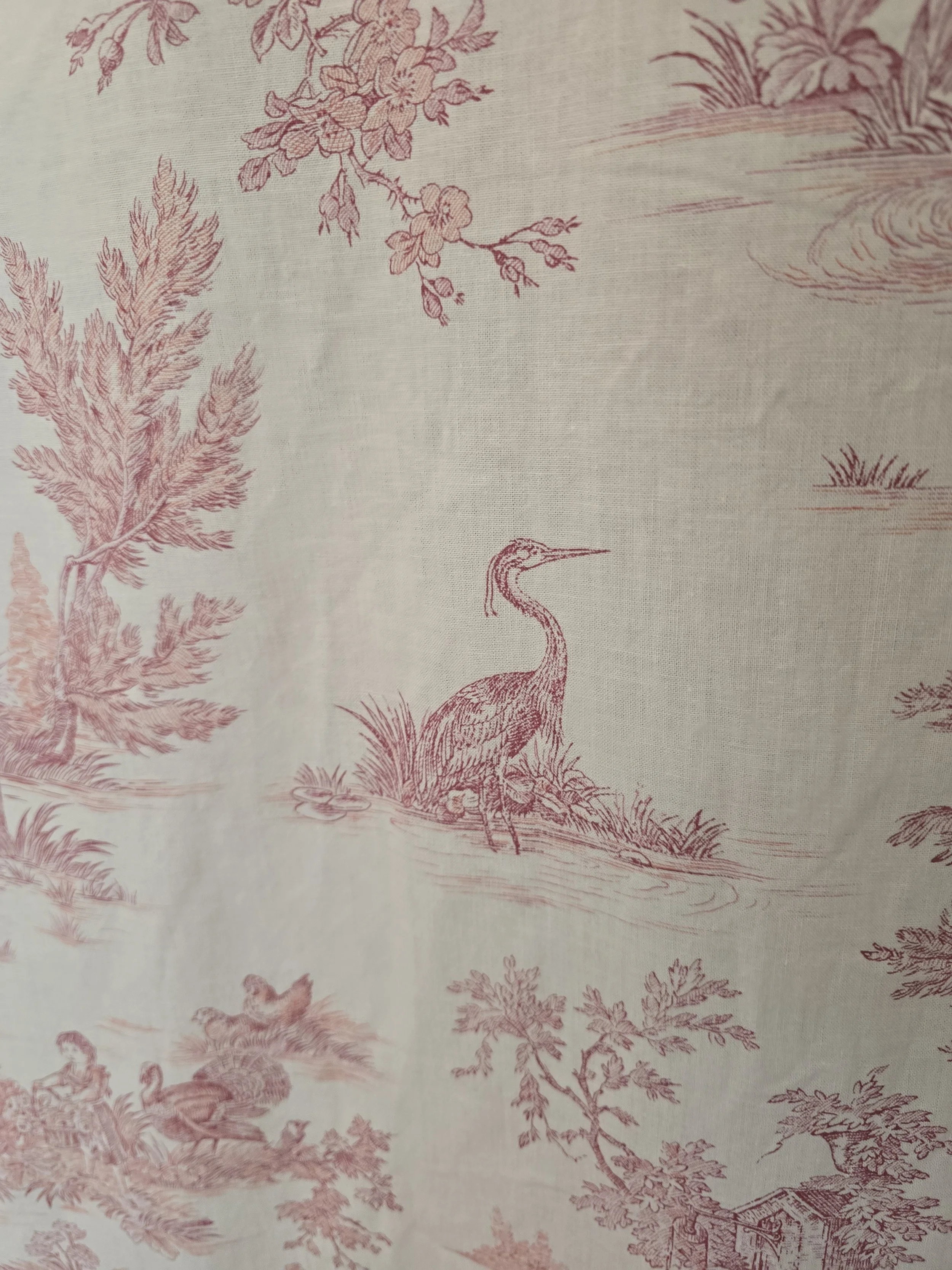 Pastorale toile fabric detail showing a heron beside water surrounded by trees and rural scenes.