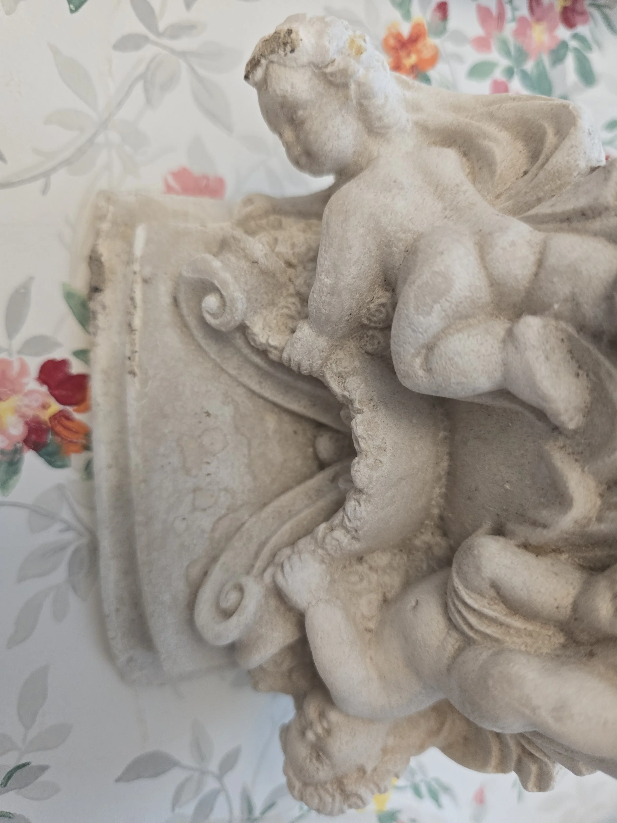 Side view of antique cherub shelf support with carved detailing.