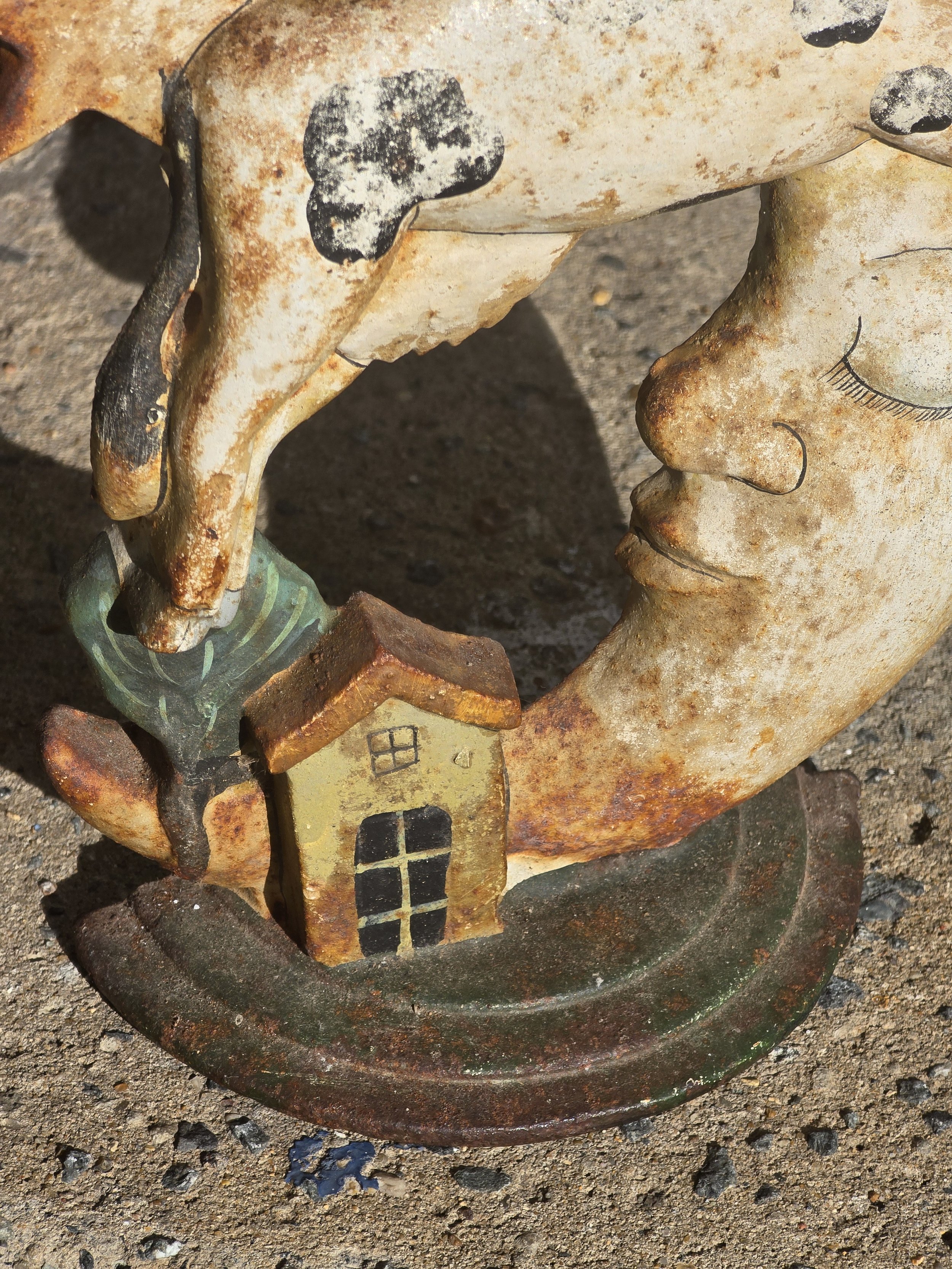 Full front view of vintage cow jumping over the moon folk art ornament with stars, faded paint and richly rusted patina.