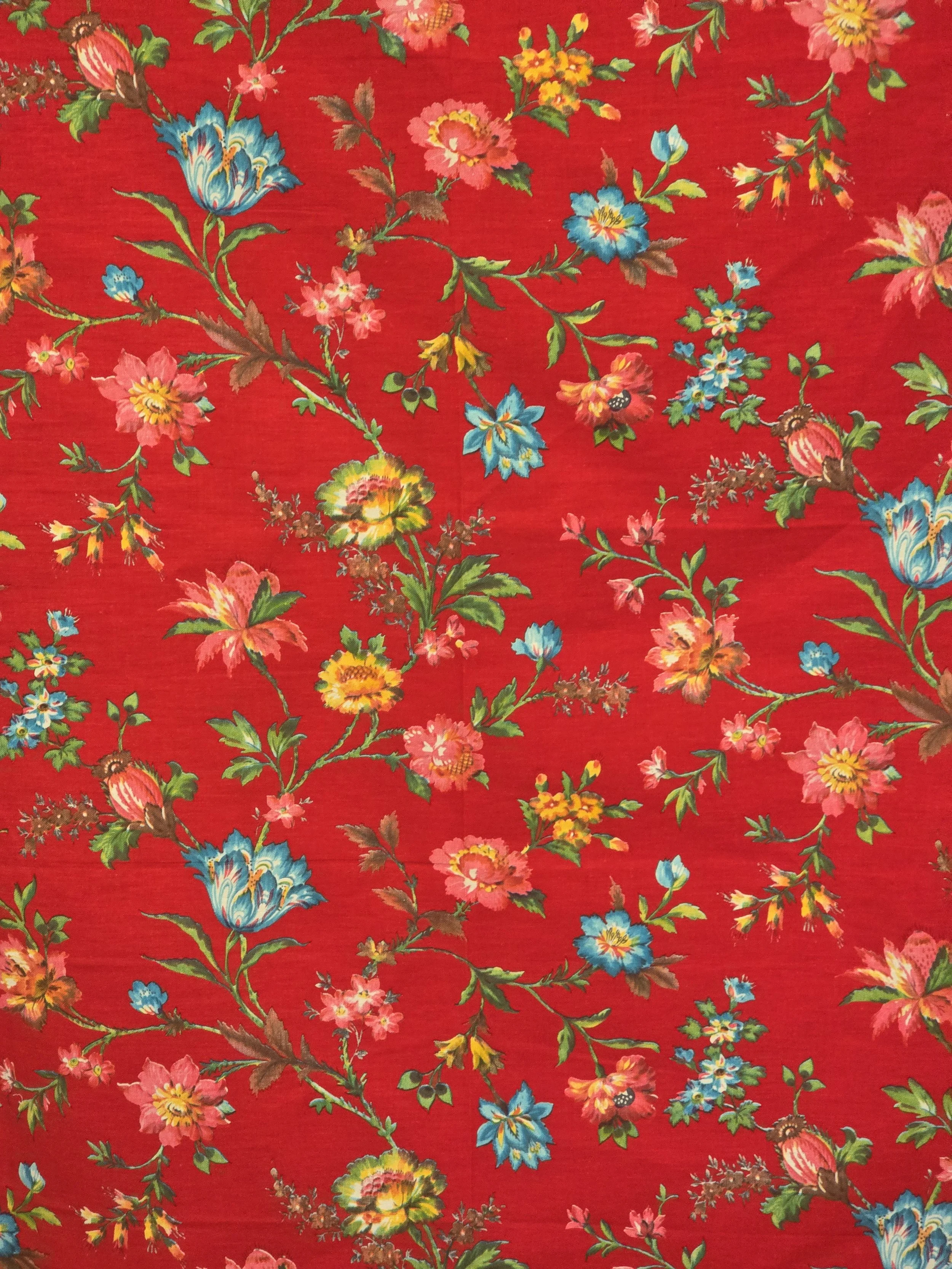 Unused vintage floral furnishing fabric with colourful flowers scattered across a rich red ground.