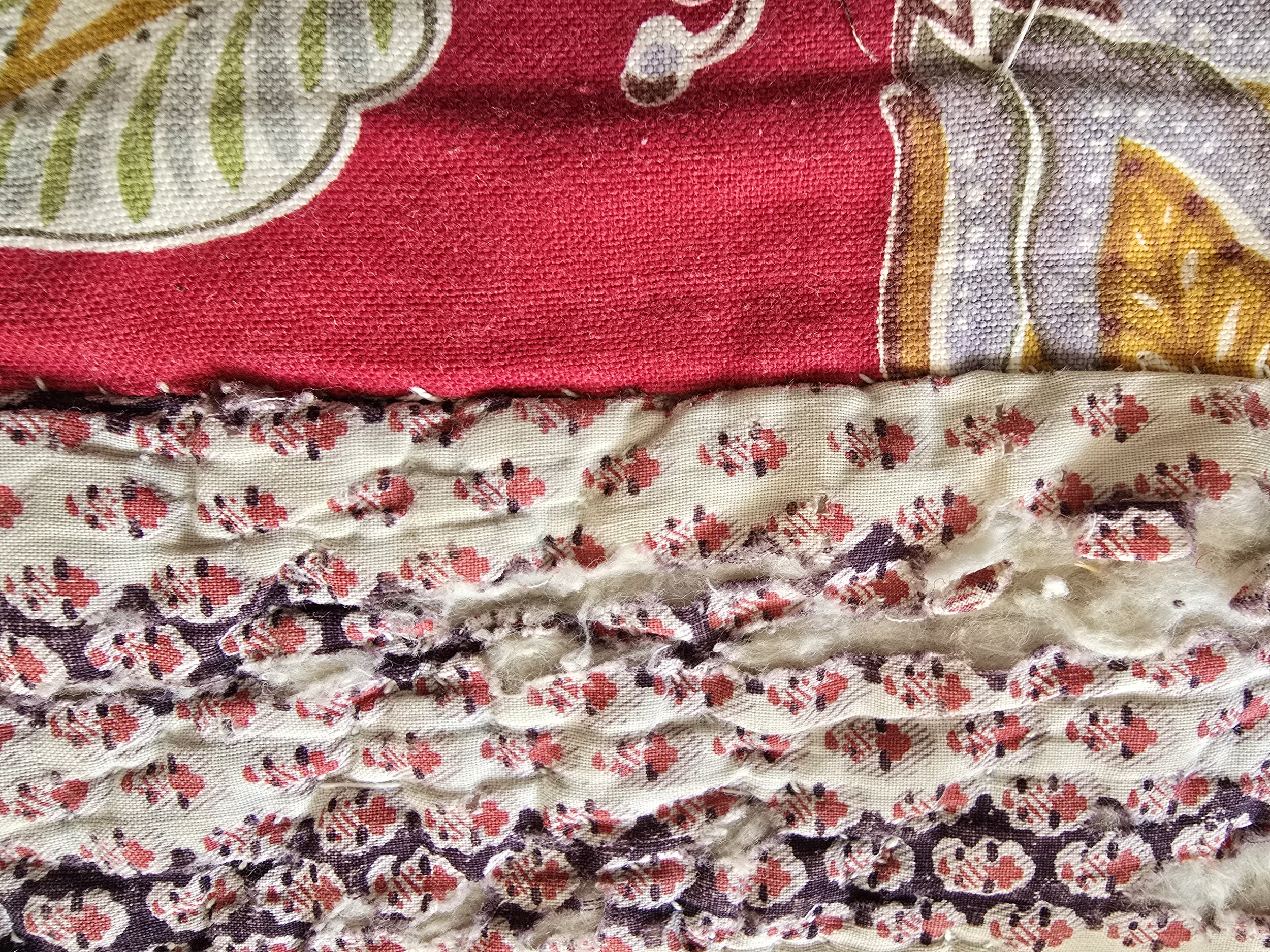 Visible wool wadding and torn seam on antique quilt