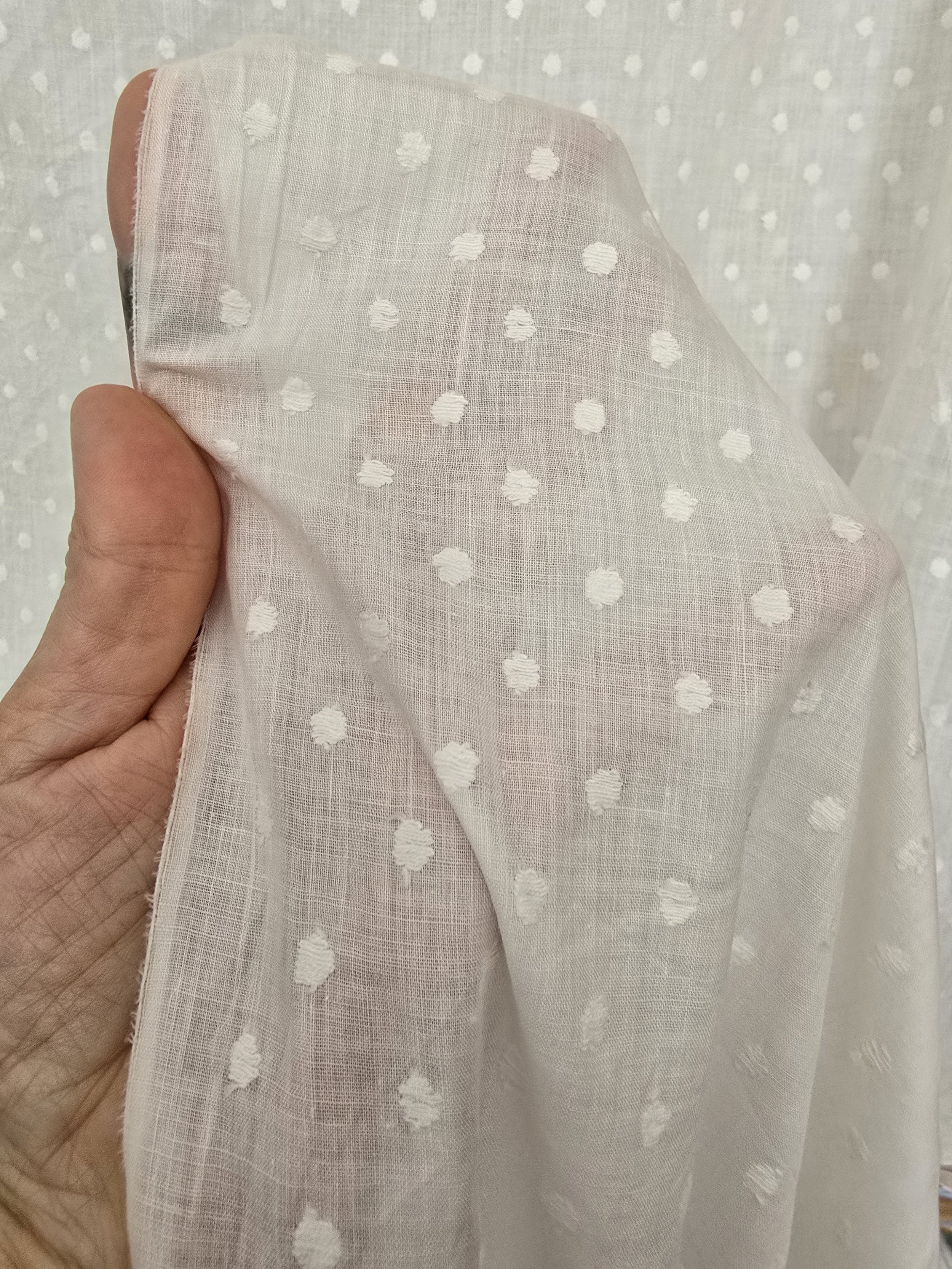 Swiss dot fabric held up to show transparency