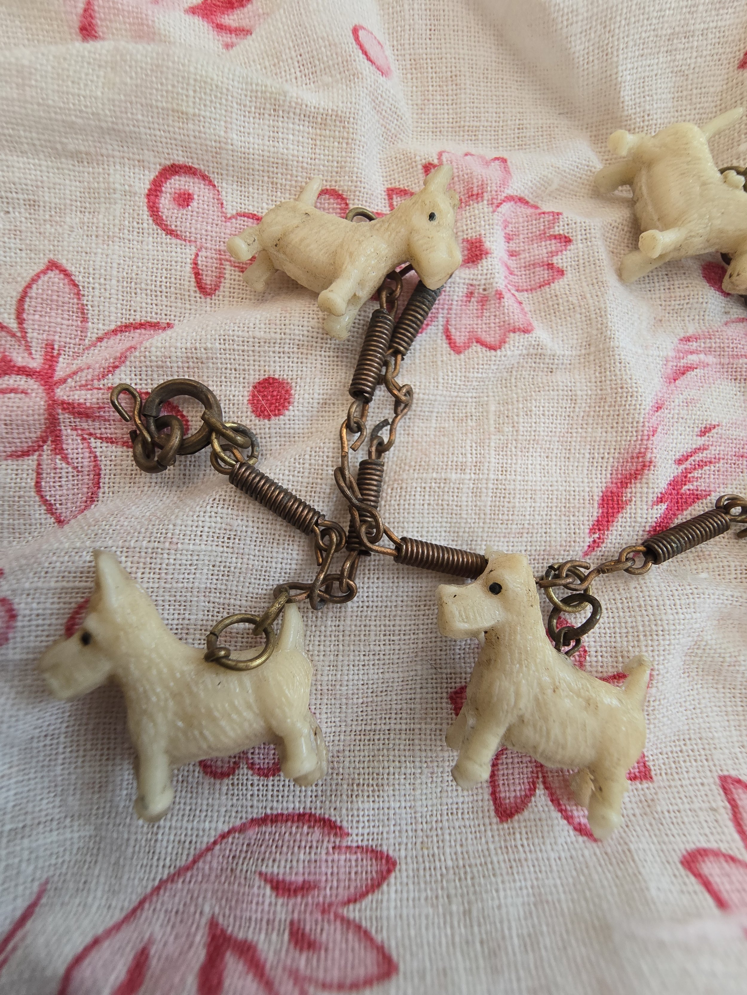 Close-up of miniature dog charms with textured fur and painted eyes on vintage bracelet.