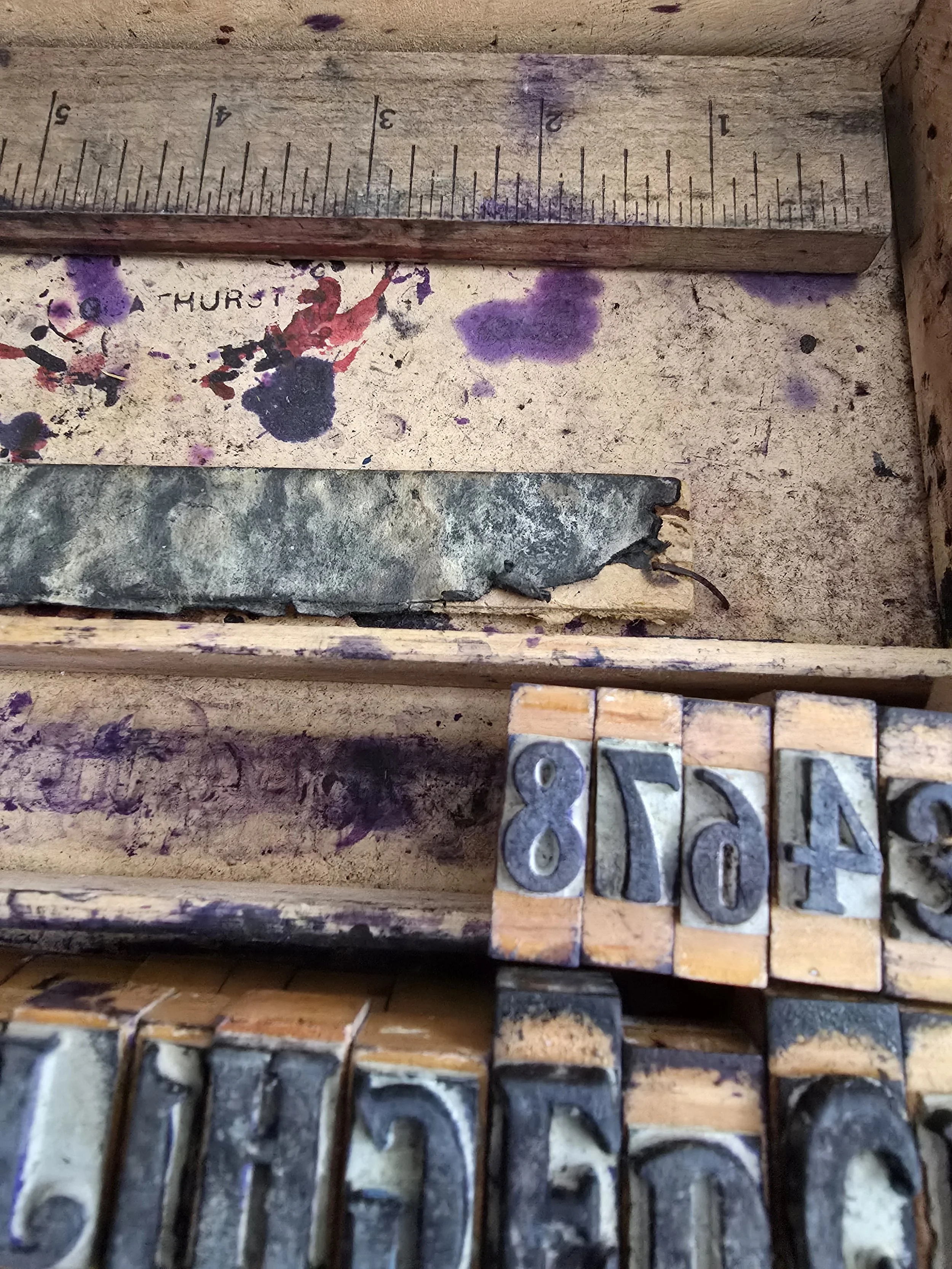 Inside of ink-stained wooden box containing vintage stamp set.