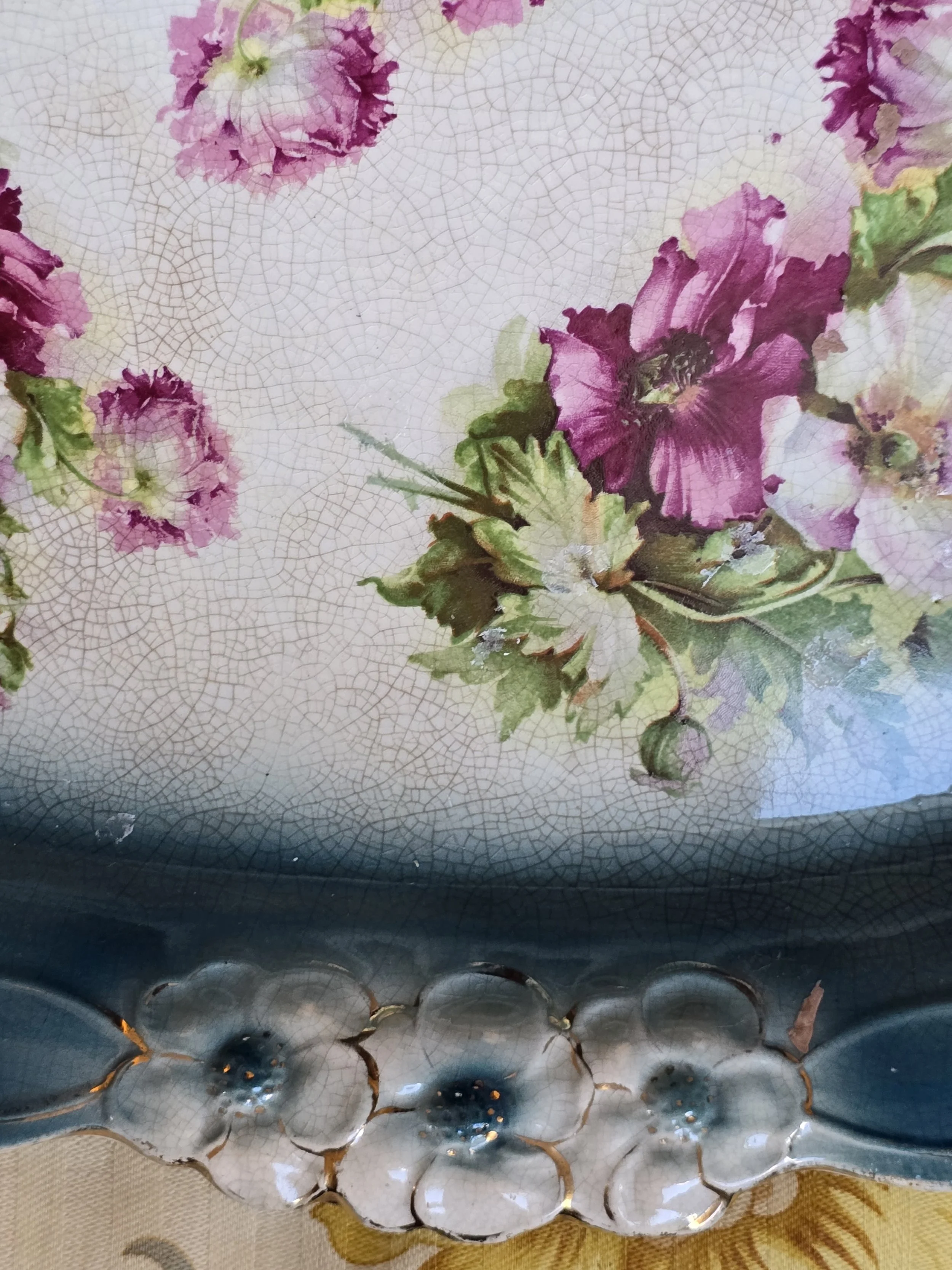 Detail of pink and plum flowers on the heavily crazed cream centre of a vintage ceramic tray.