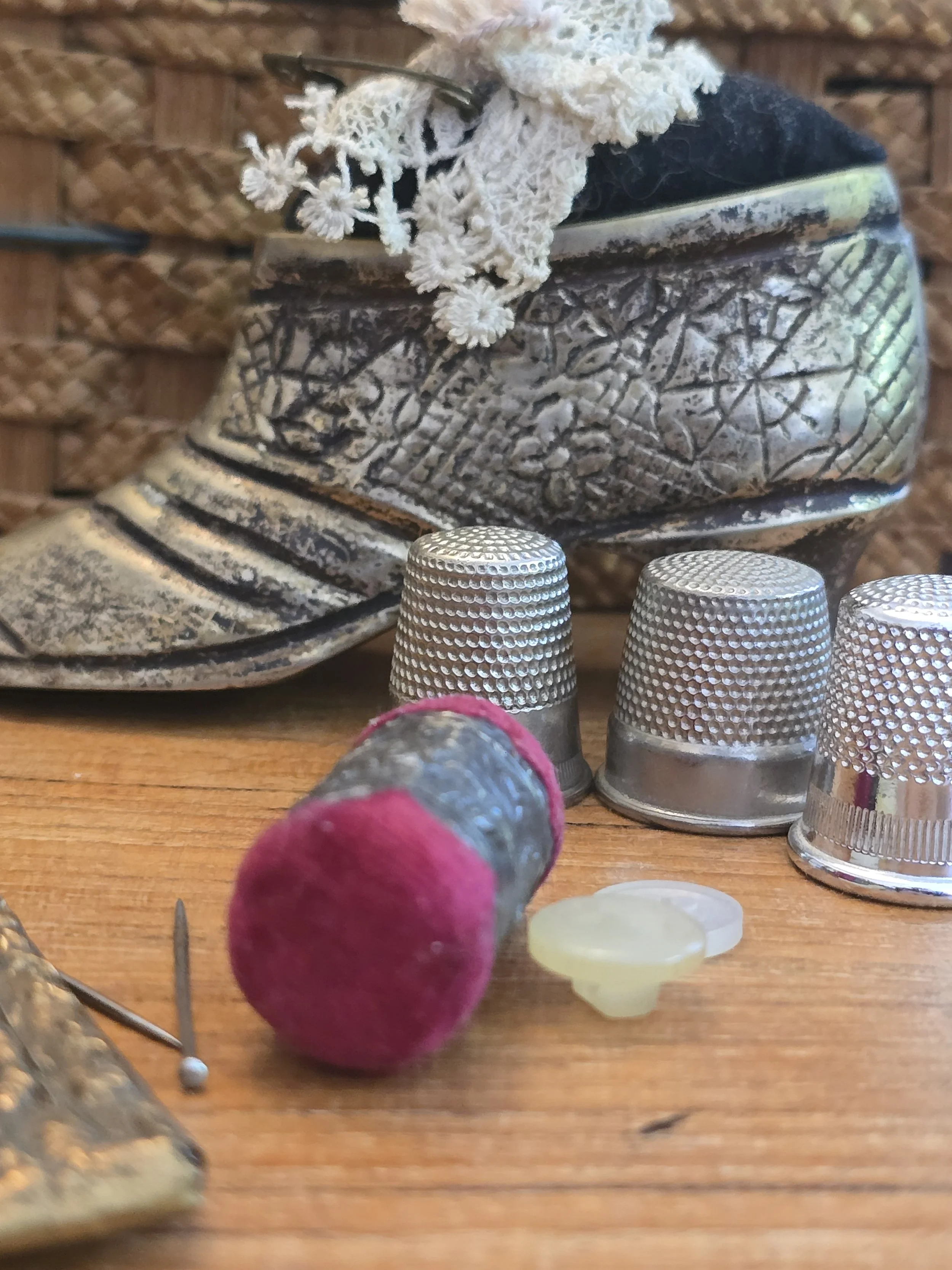 Antique emery sharpener displayed amongst thimbles and sewing notions.