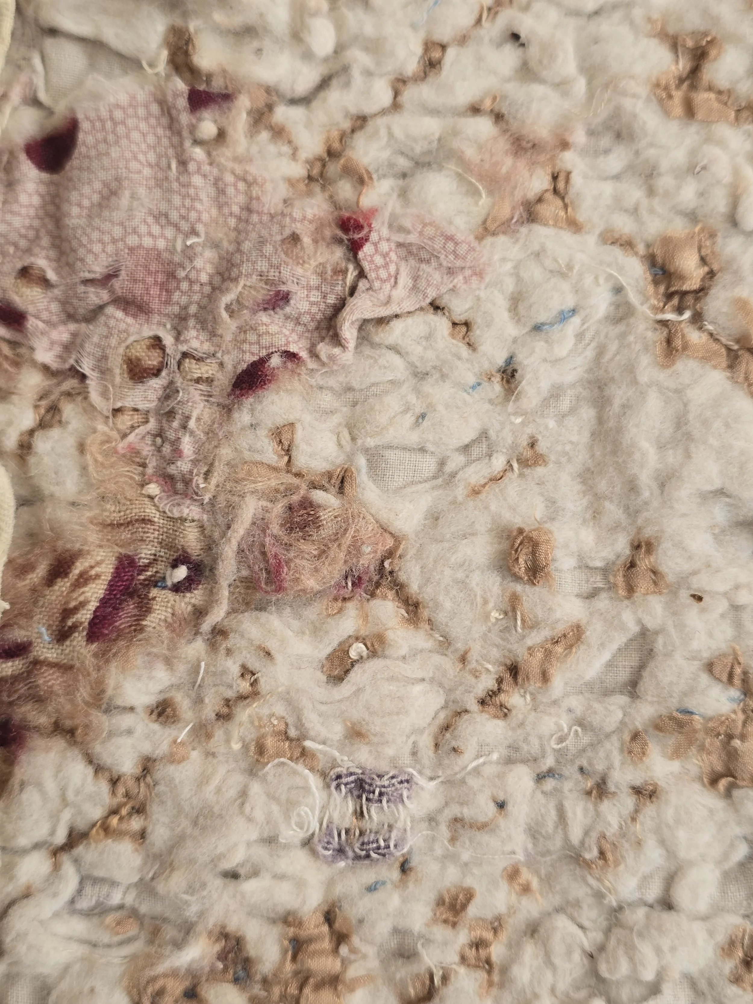 Antique French quilt fragment with faded purple printed cotton and exposed layers.
