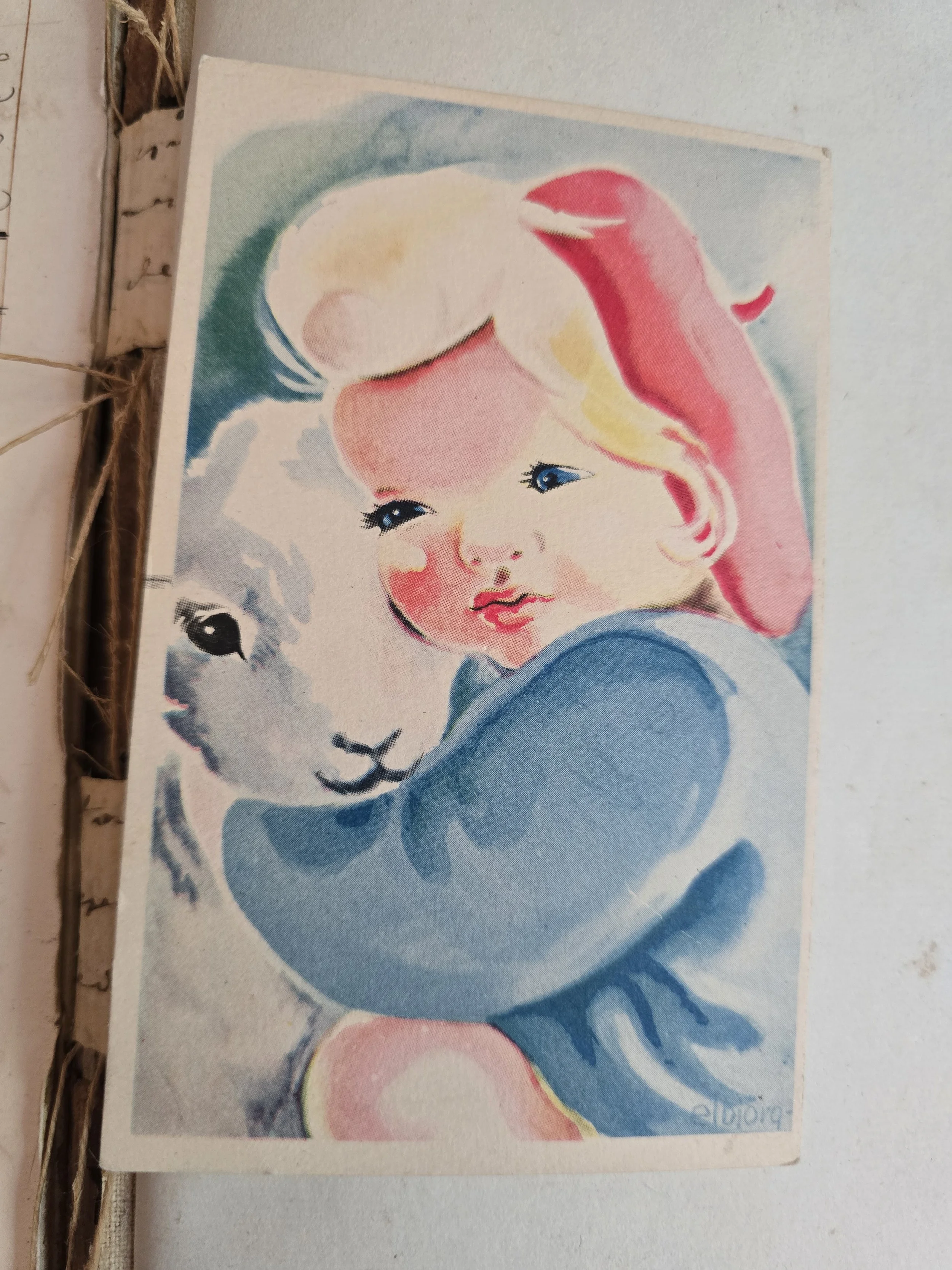 Vintage Scandinavian postcard of a child cuddling a white lamb.