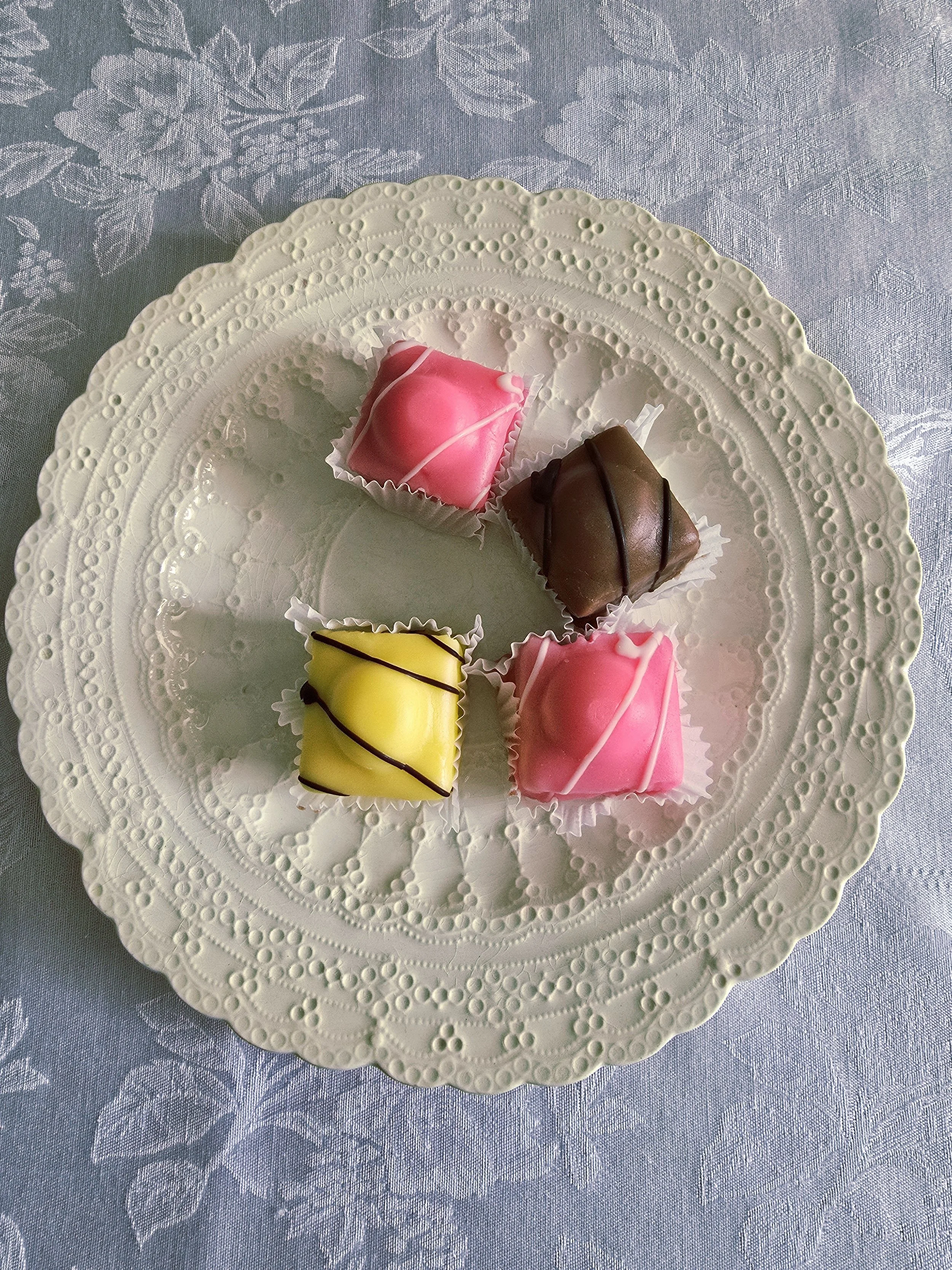 antique embossed ceramic plate styled with colourful sweets on a blue floral cloth