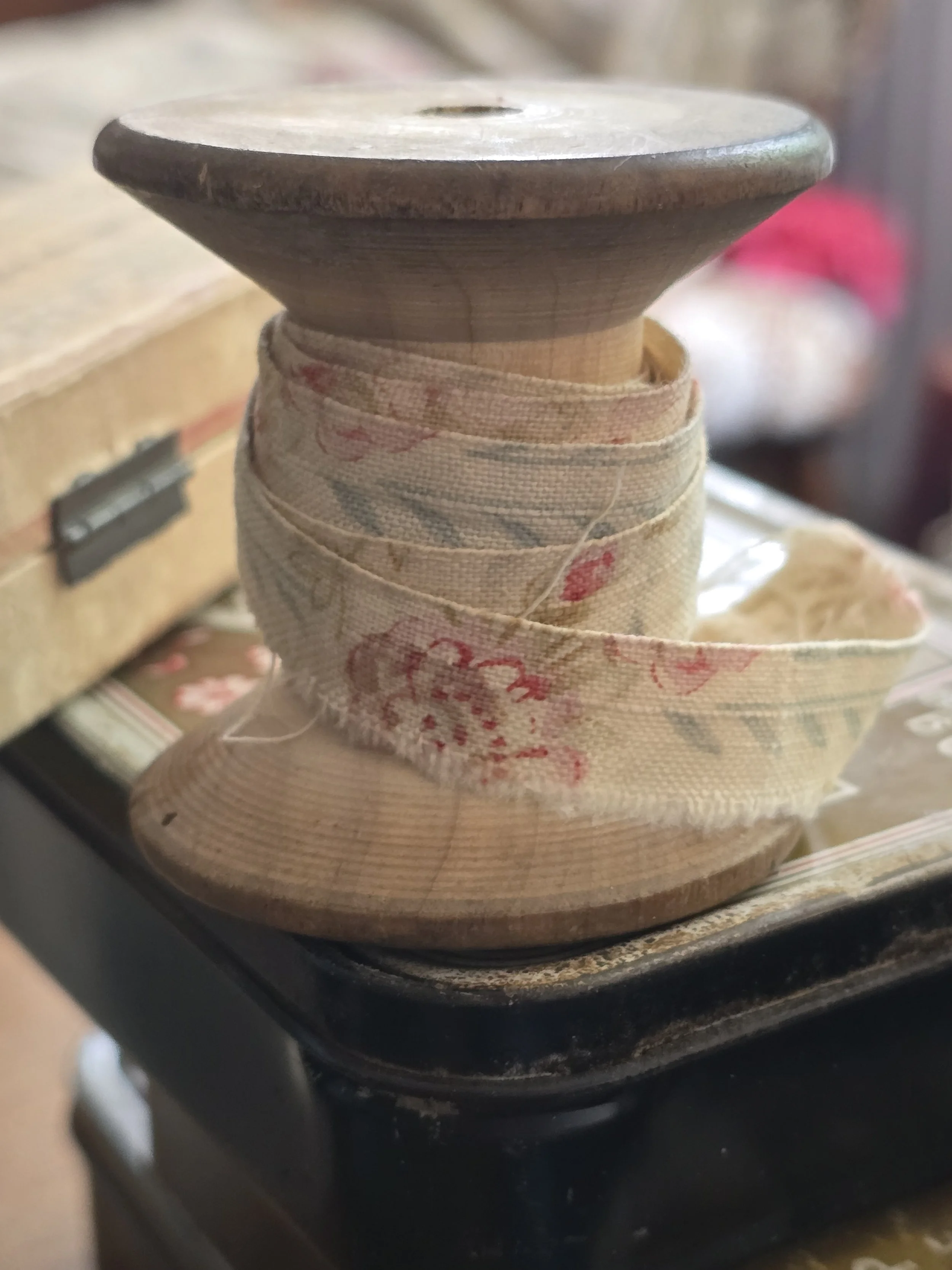 close up of antique spool wrapped in antique floral fabric trim