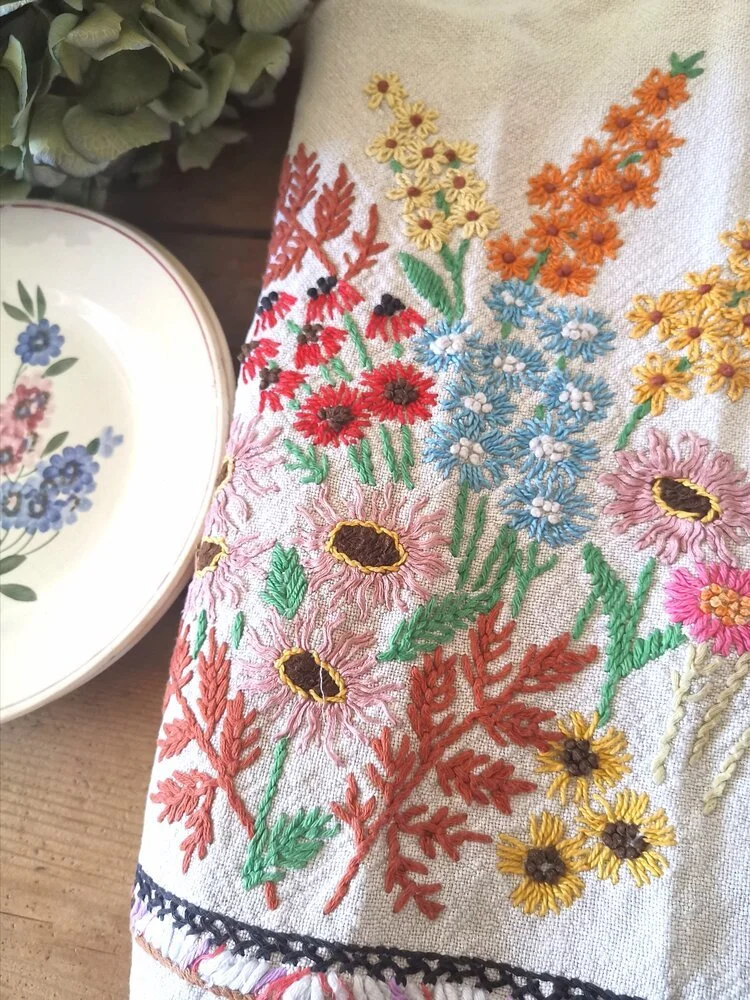 Corner of rare vintage French hemp tablecloth with hand-embroidered flowers in orange, pink, and blue