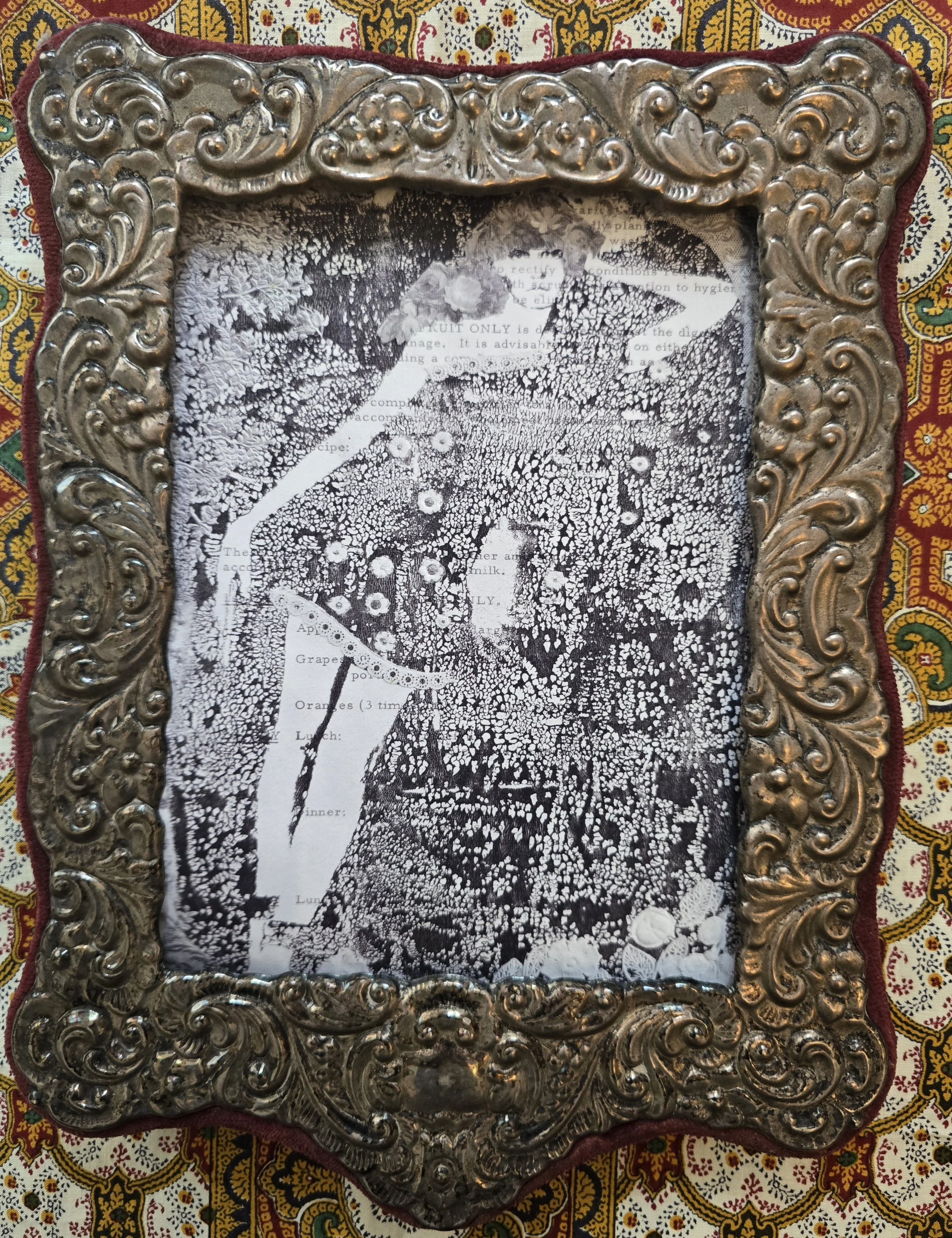 Late Victorian ornate silver-tone easel frame with decorative scrollwork and artwork insert.
