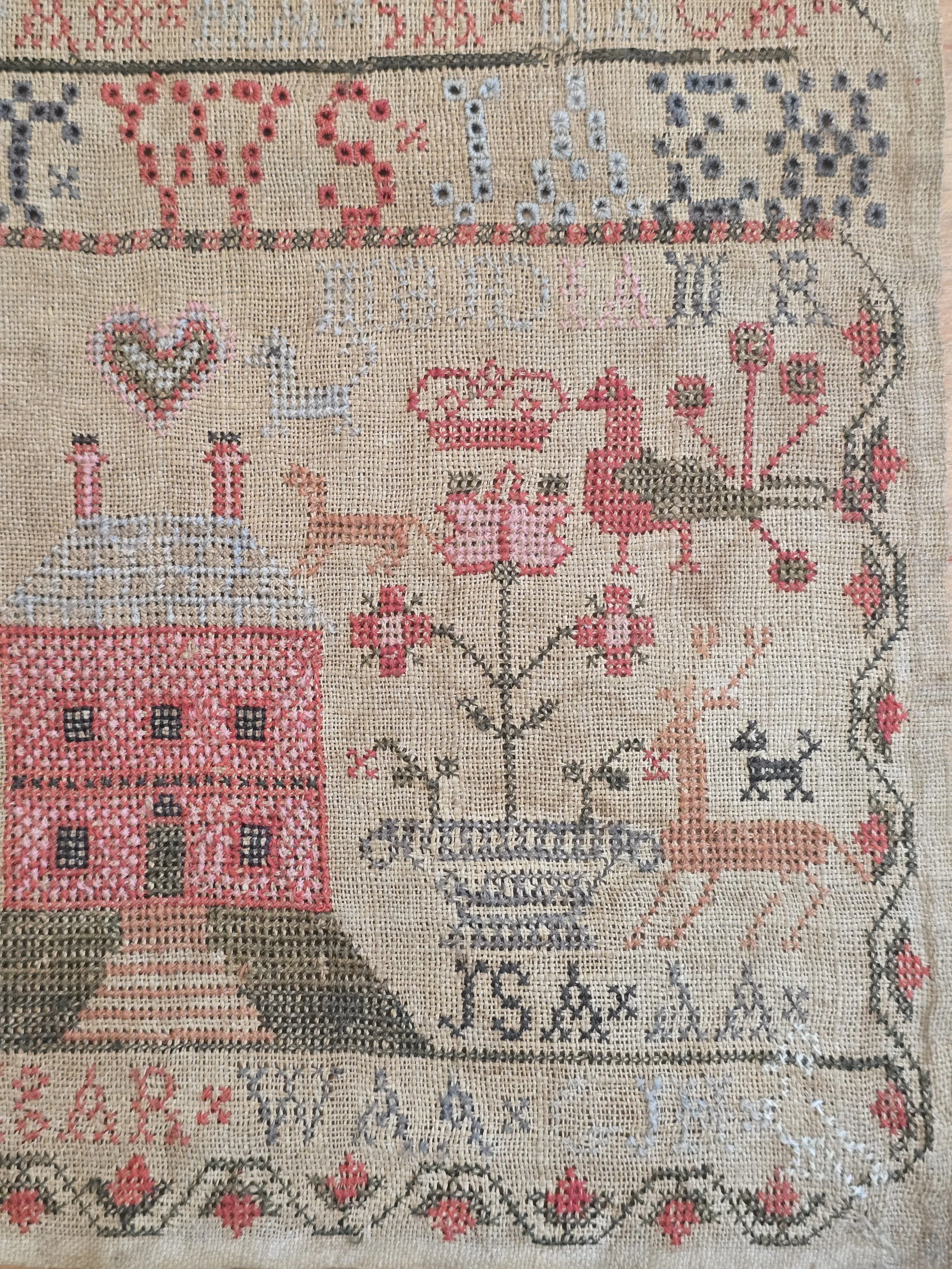 Antique Scottish folk art sampler showing embroidered birds, deer, flowers and decorative borders on aged linen.