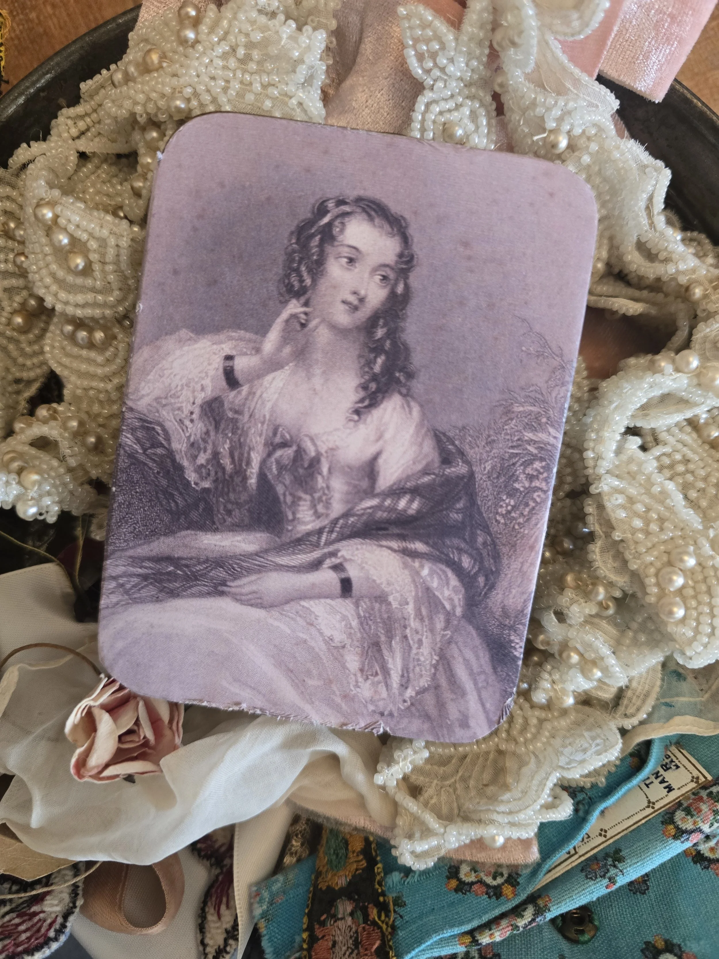 Close-up of scanned antique female portrait in mauve tones applied to a small vintage tin.