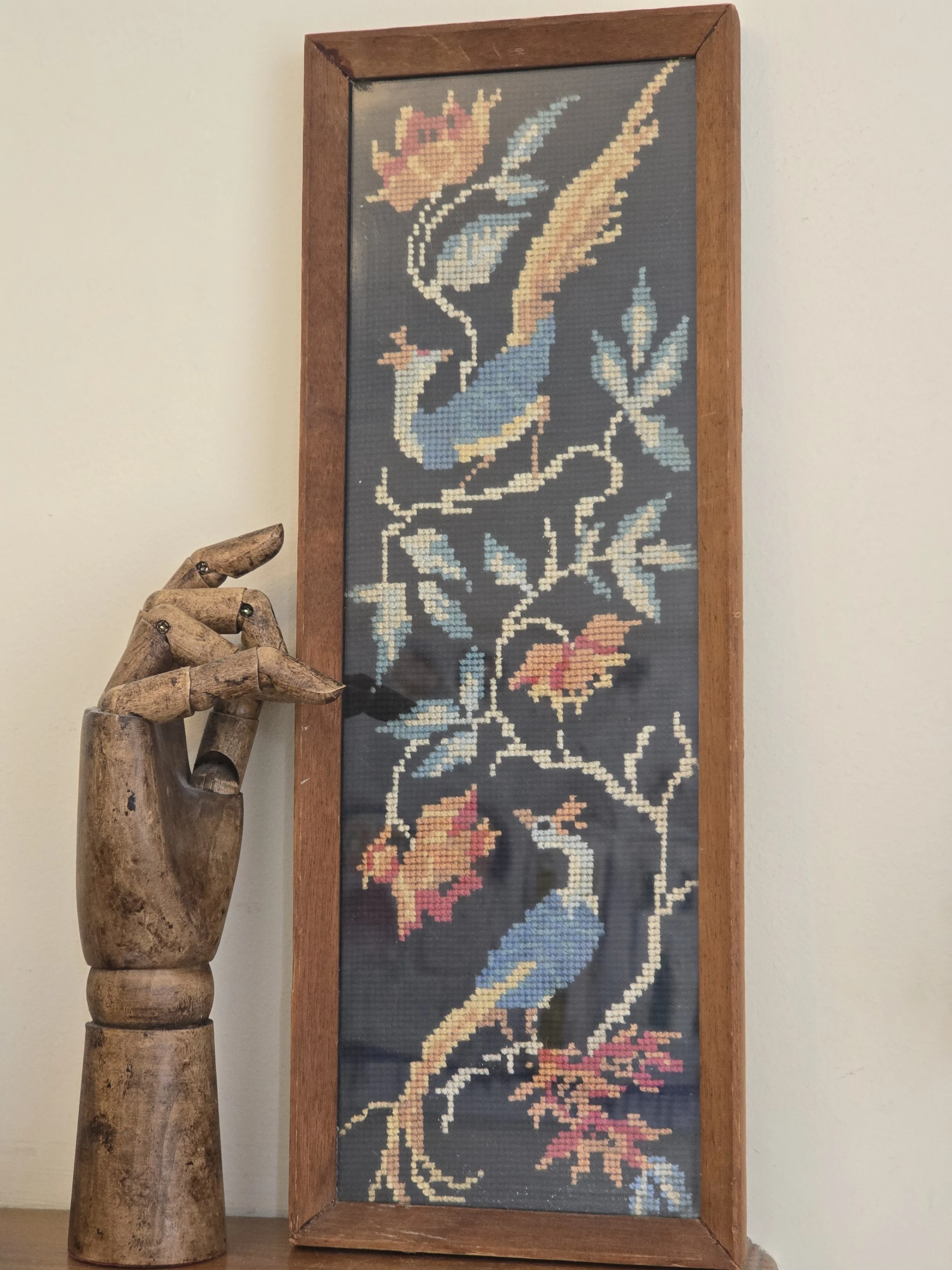 Vintage framed needlework depicting two colourful peacocks and flowers on a dark ground