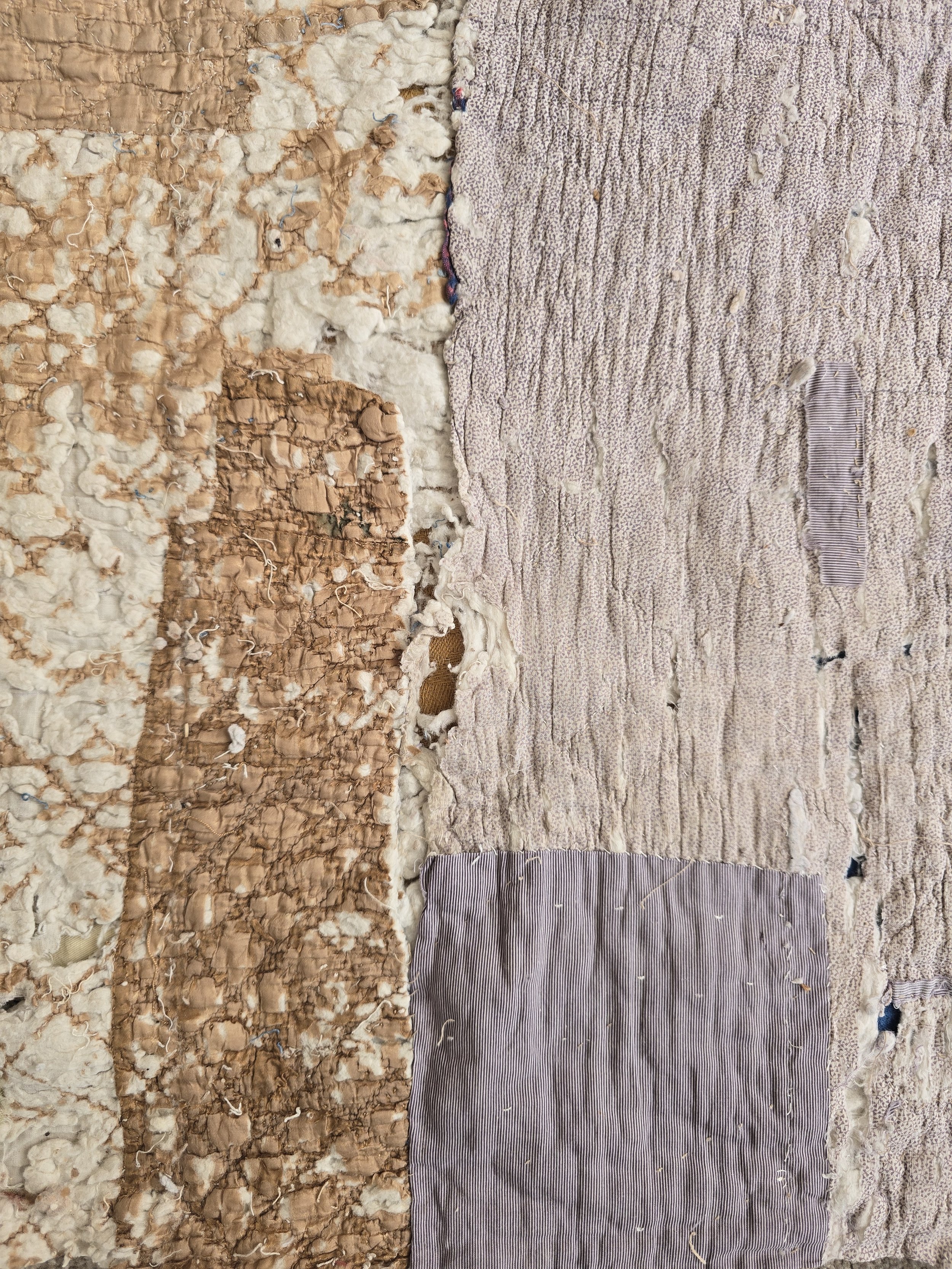 Antique French quilt fragment with faded purple printed cotton and exposed layers.