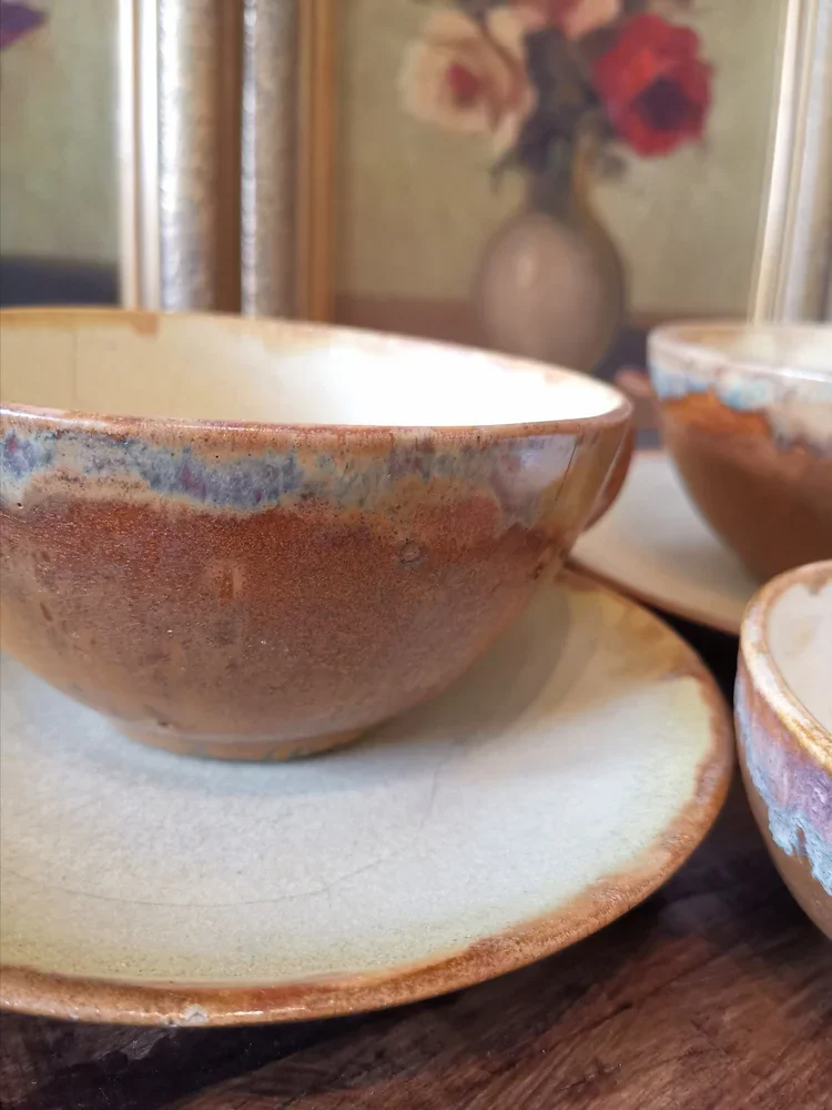 Pair of antique Charles Gréber cups with saucers, showing glaze variation and wood-fired surface texture