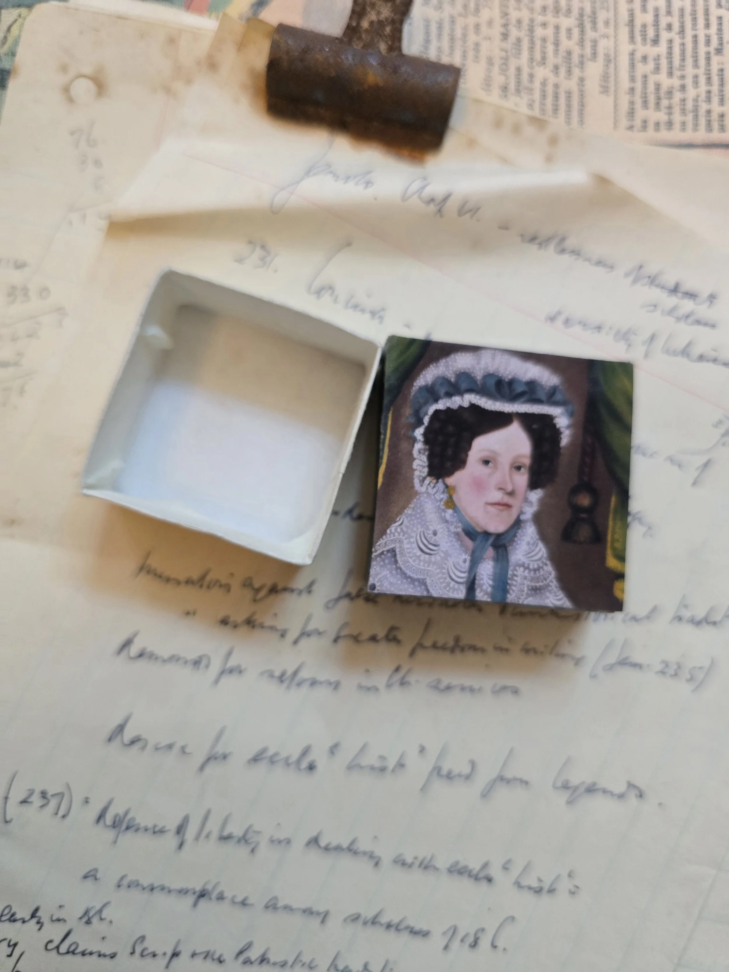 Tiny 4 cm vintage jewellery box opened to show its original white interior and portrait decorated lid.