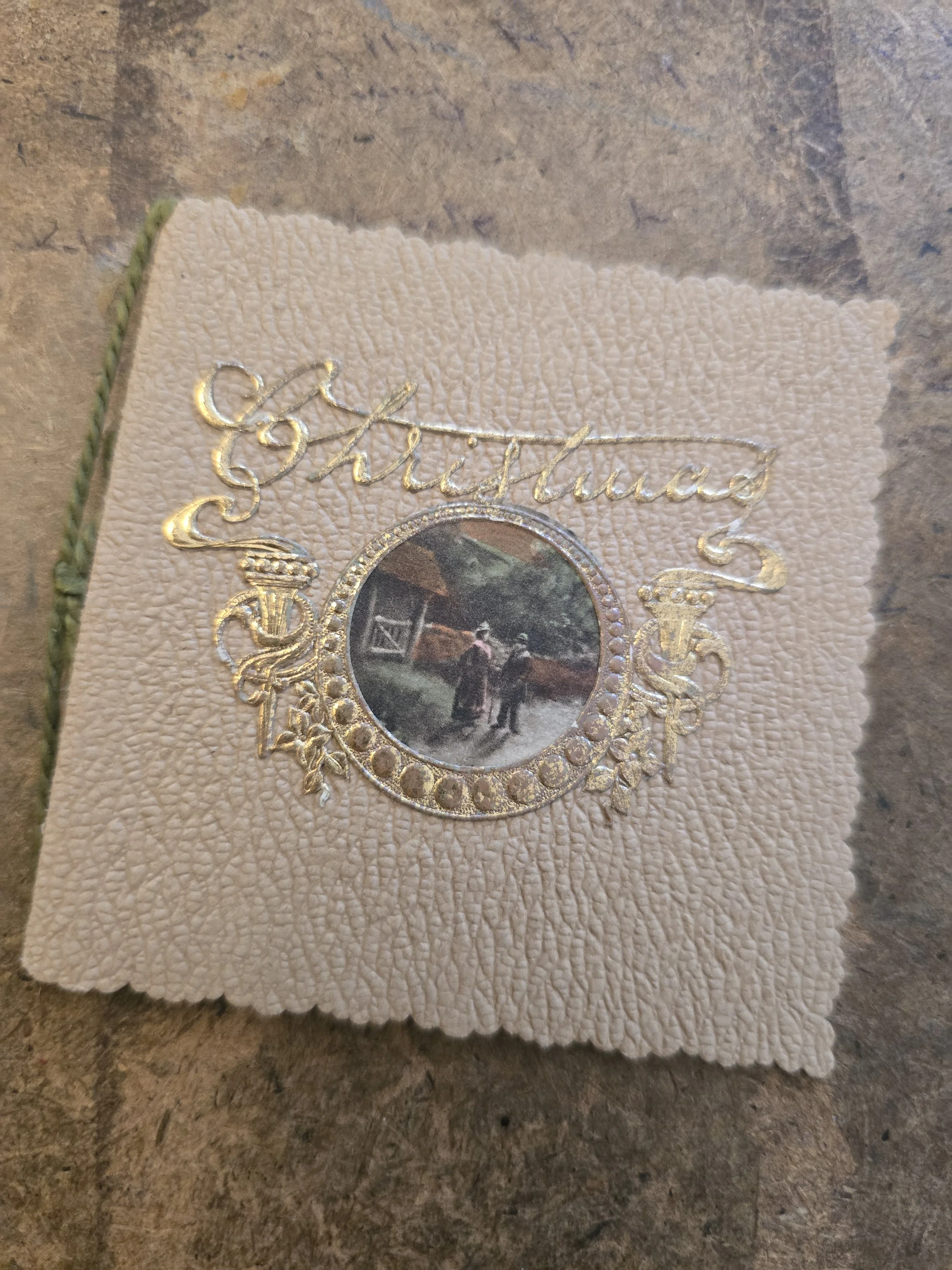 Antique French Christmas card circa 1910s with ornate gilt decoration and tiny pastoral scene, measuring 8 x 8 cm.