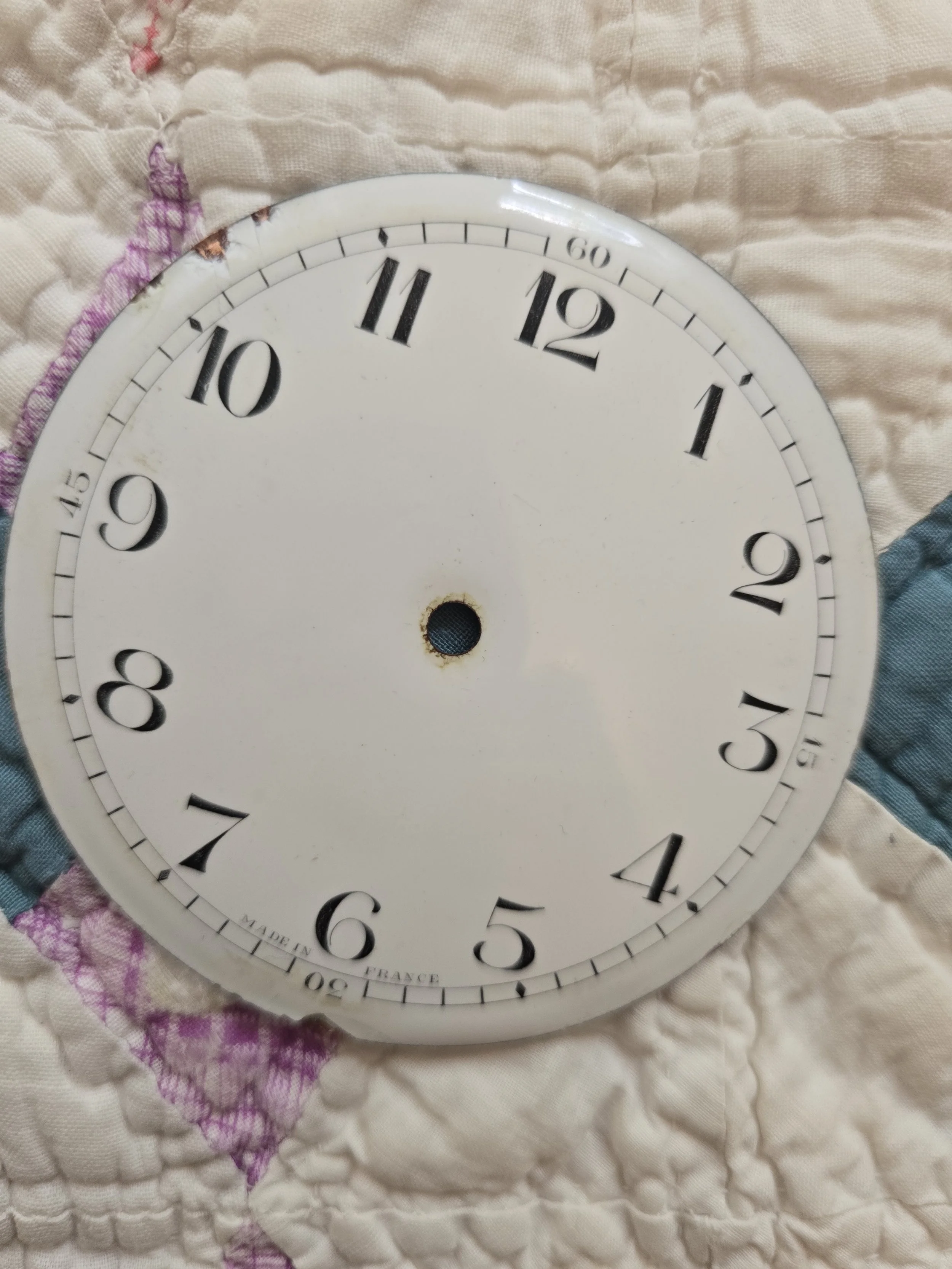 Antique French enamel clock dial with black Arabic numerals and age-related wear.