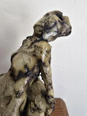 Side view of reclining ceramic figure sculpture with rough textured surface