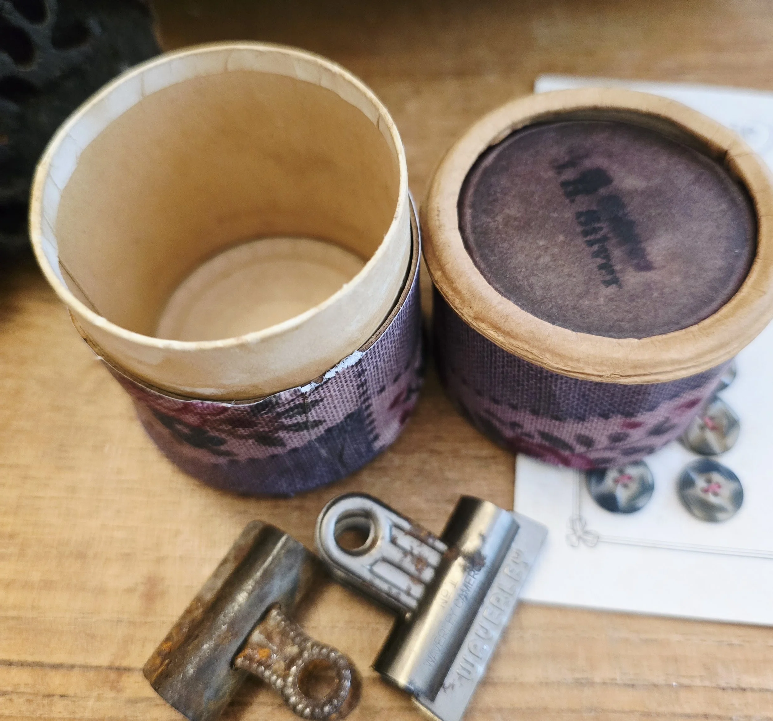Open cylindrical box showing the original aged cardboard interior and decorated lid