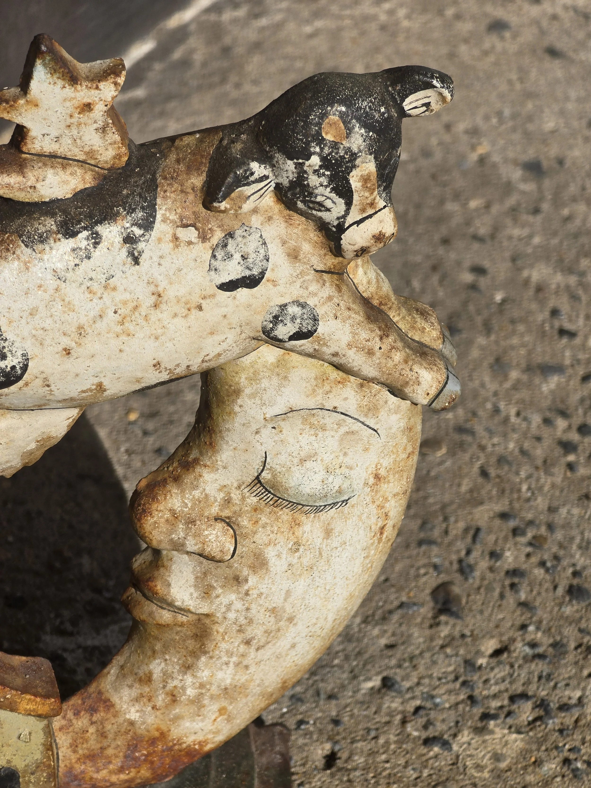 Close-up of the tiny painted house, crescent moon and heavily rusted curved metal base.