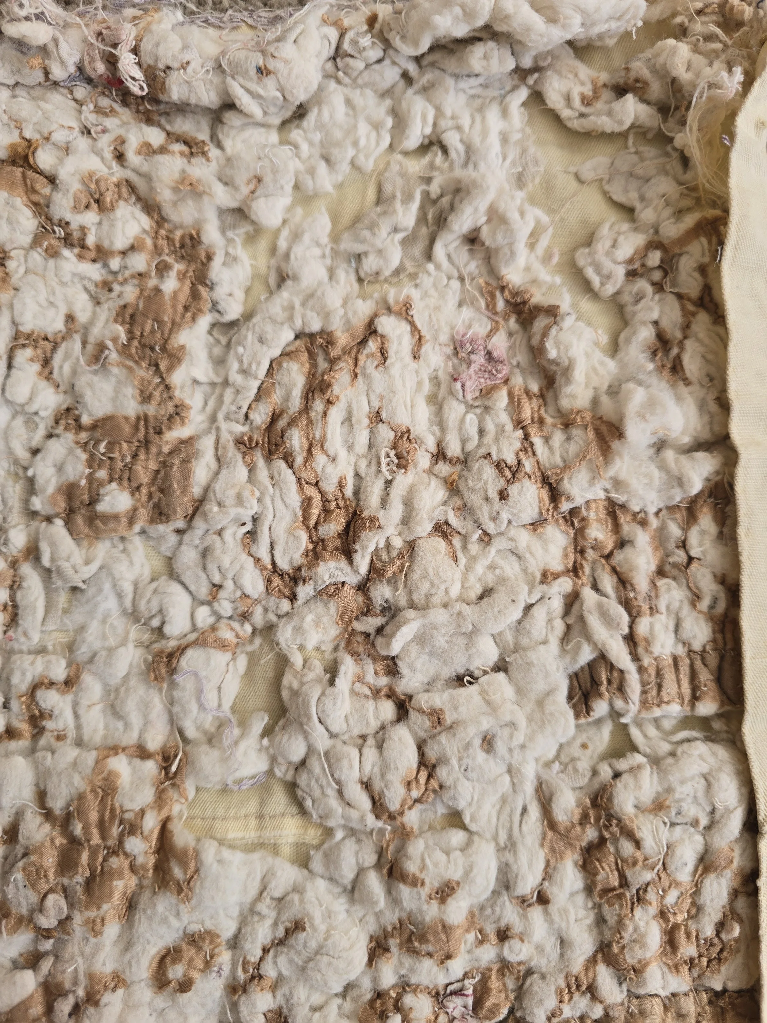 French quilt fragment showing heavily worn fabric and exposed natural wadding.