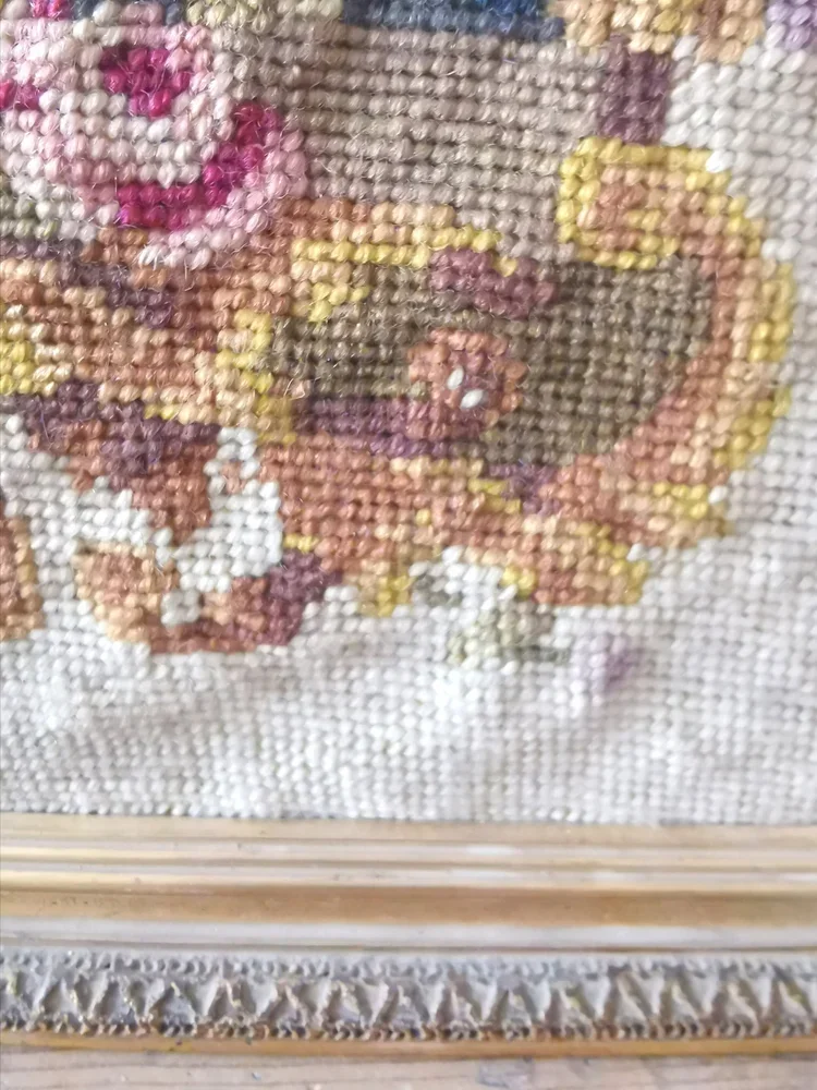 Close-up of decorative scrollwork and floral border in antique needlepoint