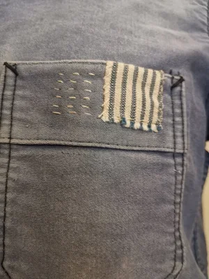 Antique ticking fabric patch stitched onto front pocket of indigo moleskin coat.