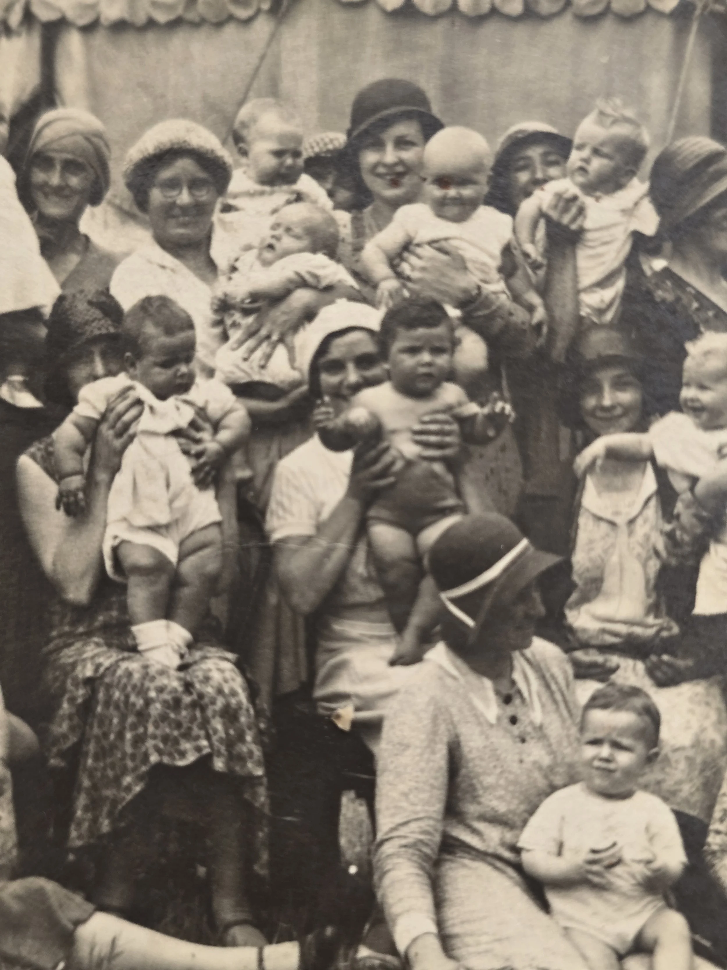 Detail of women and babies gathered in front of a large canvas big top style tent in the 1930s.