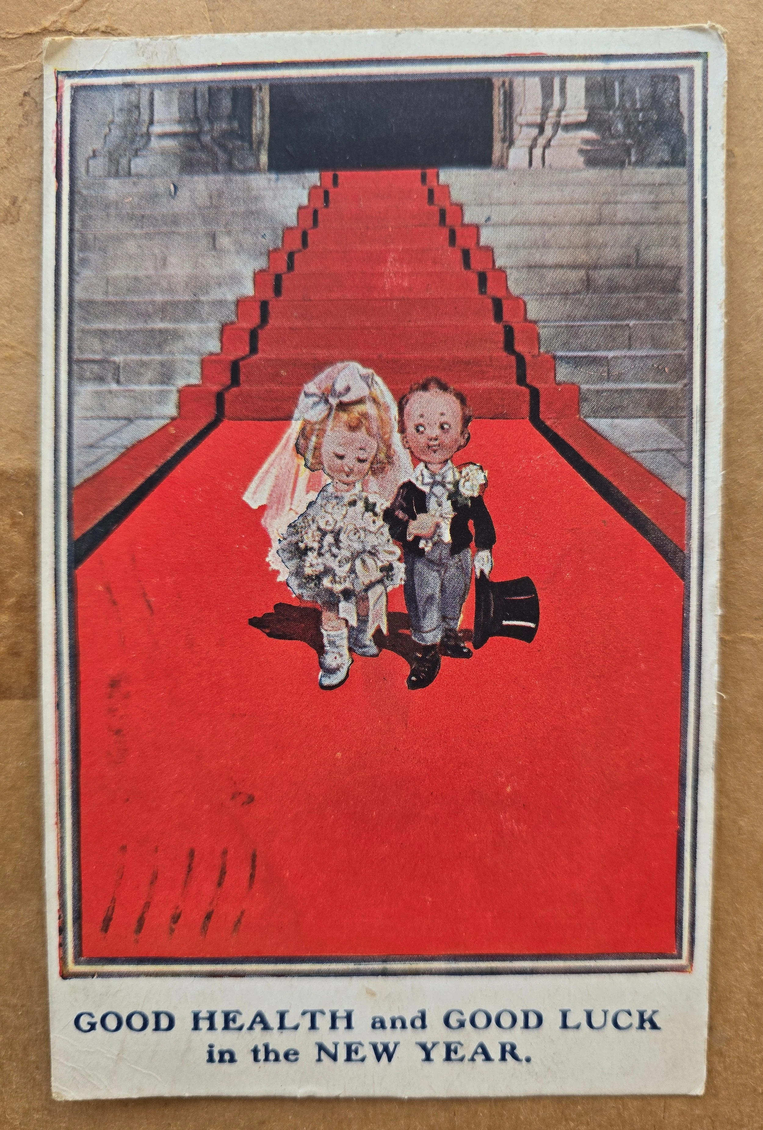 Antique 1920 New Year postcard showing a miniature bride and groom on a red carpet