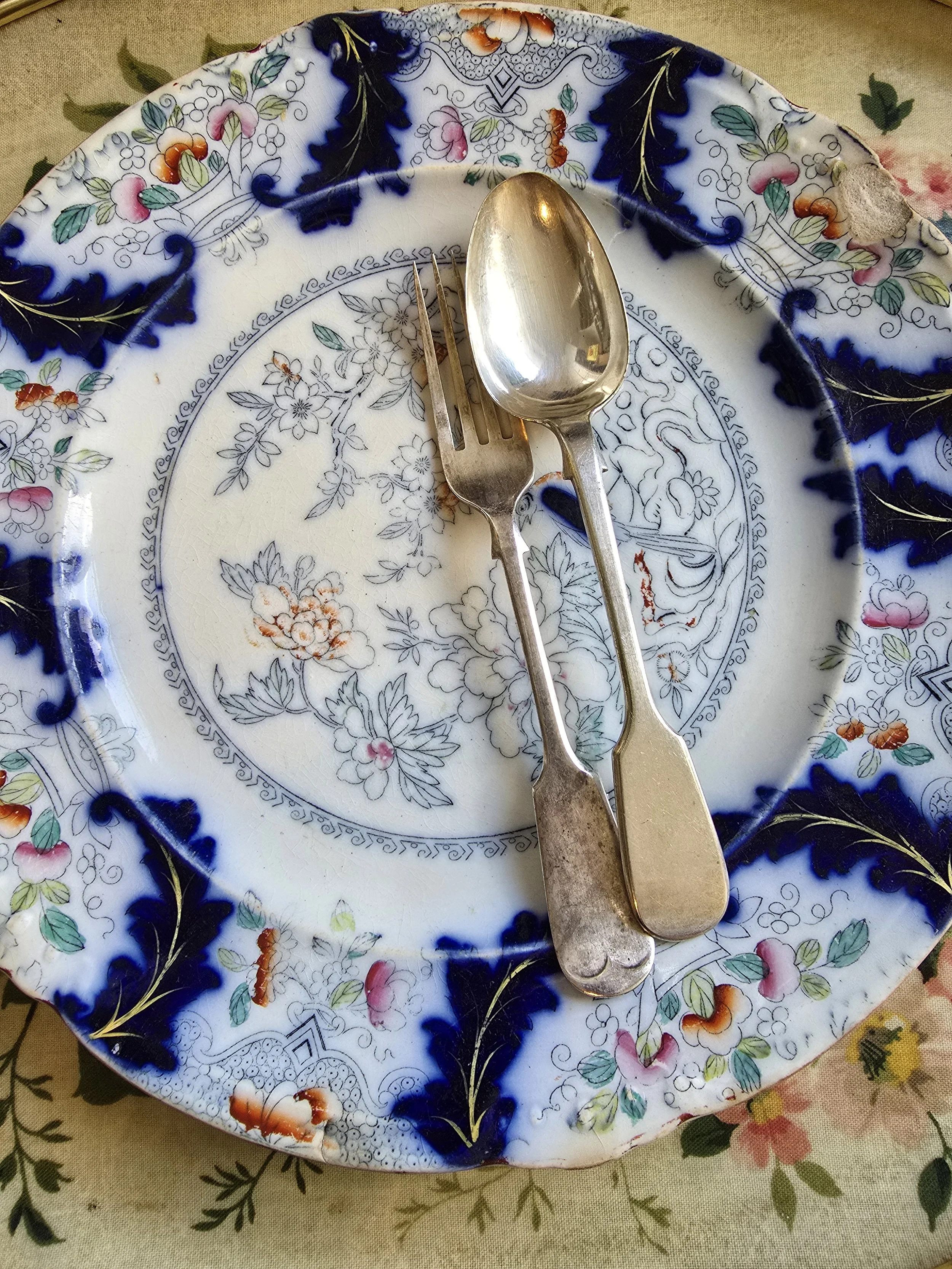 Antique Victorian sterling silver fork and spoon set, London 1837, displayed on floral antique plate