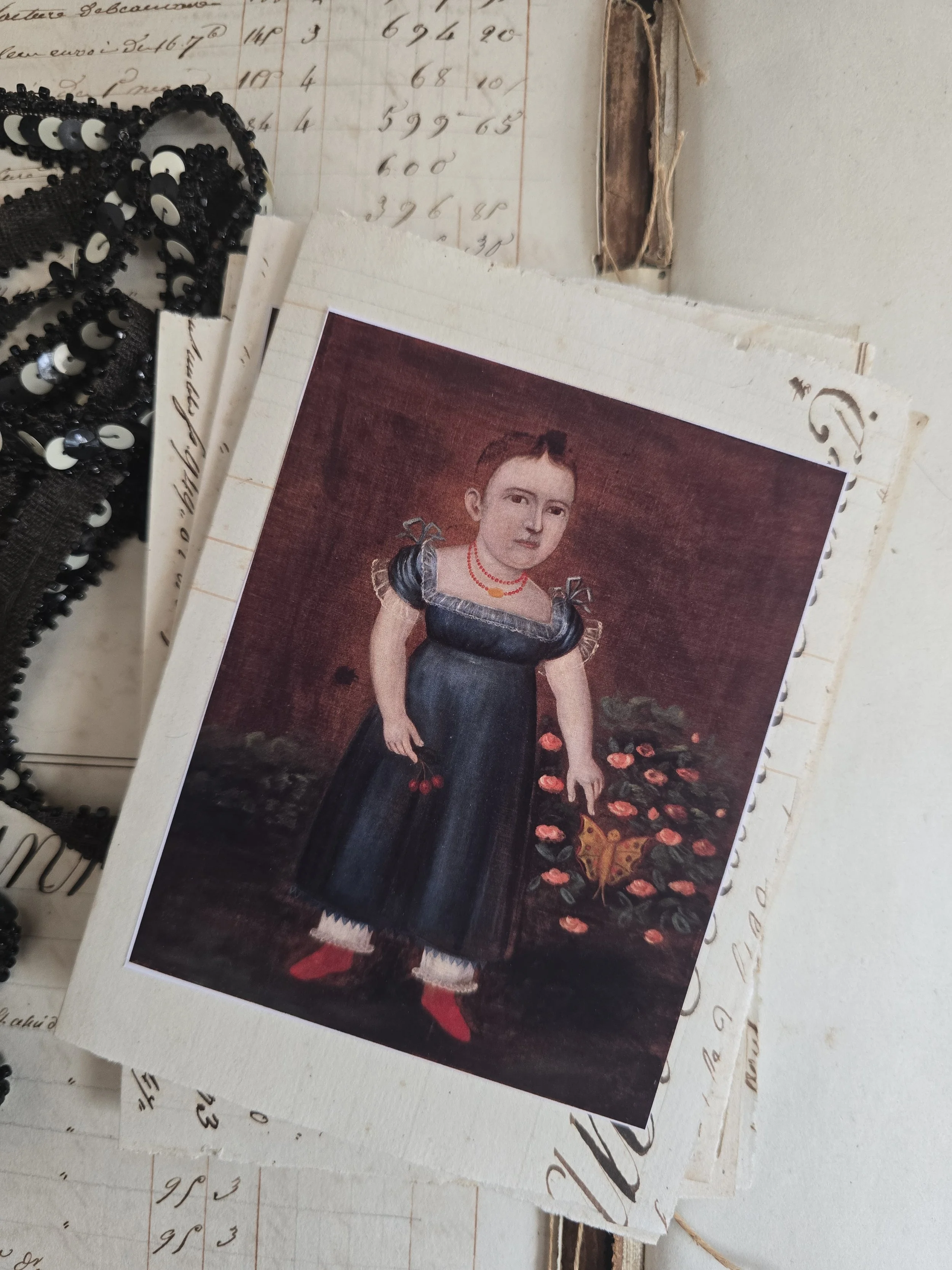 Handmade card with folk portrait of a child in a pink dress, mounted on original handwritten 1829 French ledger paper.
