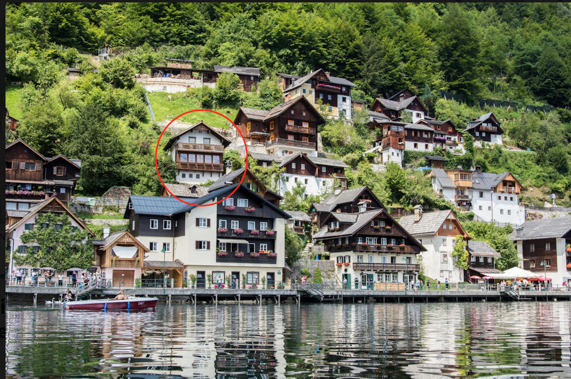 Hallstatt Häuser an einem Berg am Hallstätter See, typische Häuser aus Holz, mit Menschen am Ufer, und ein Boot im Wasser.